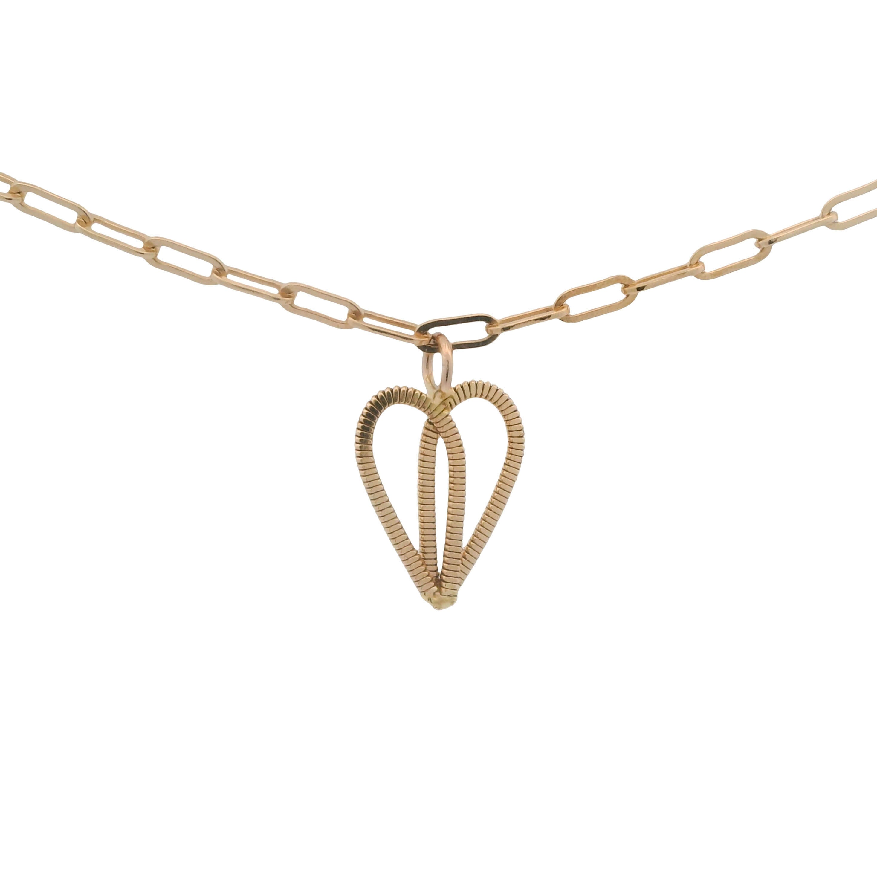 Gold guitar string heart on gold paperclip chain with white background.