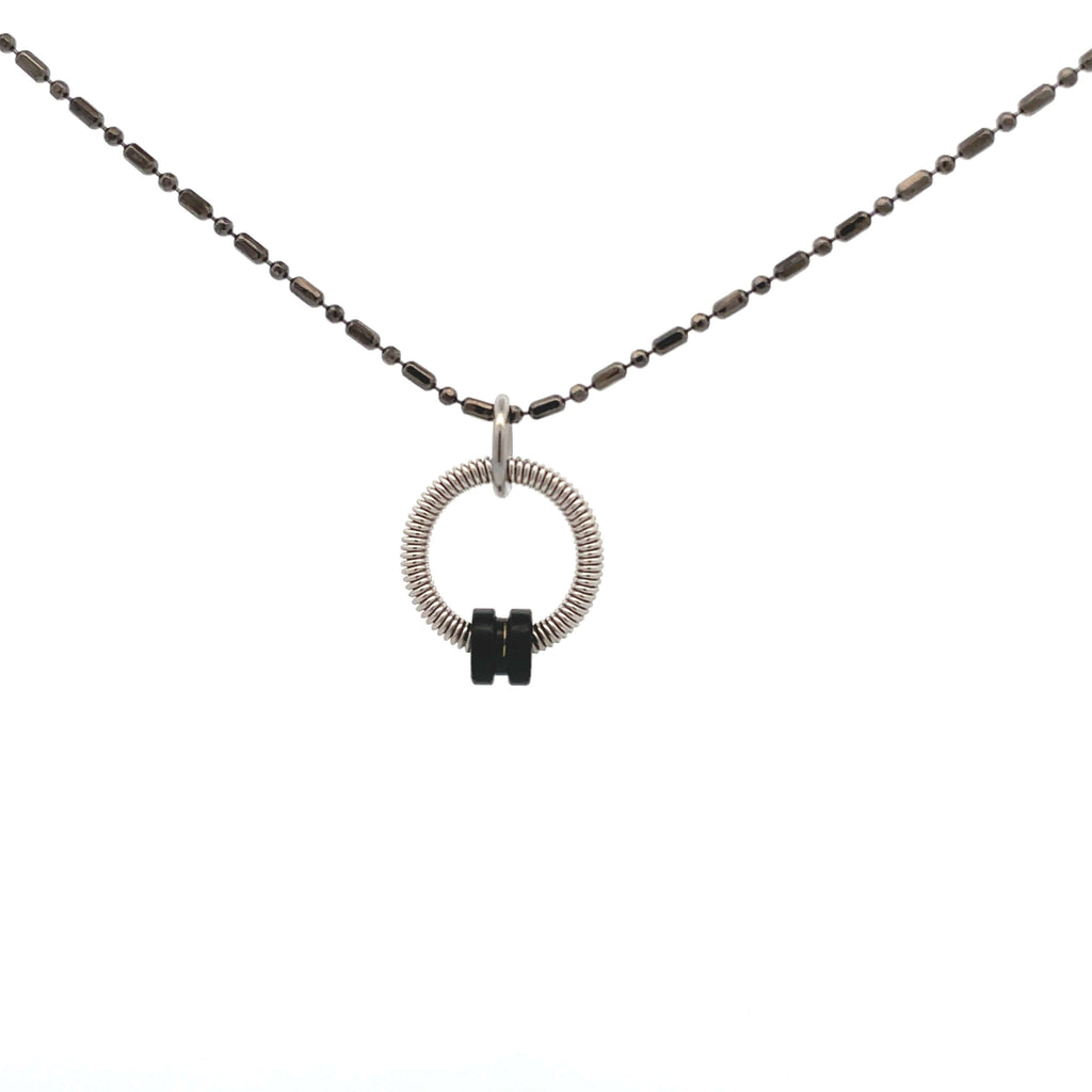 Bass guitar string necklace with black ball end on white background