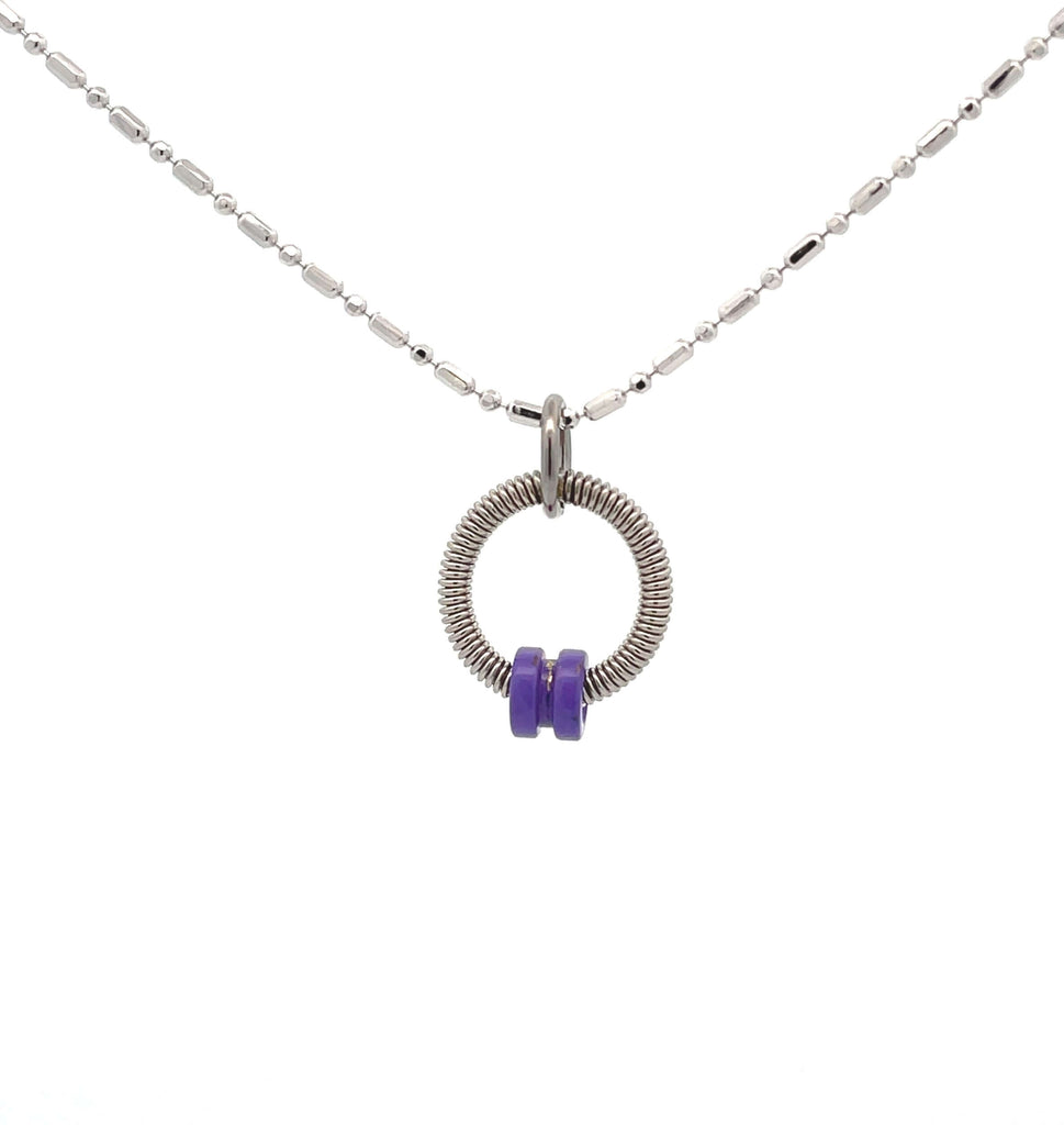 Bass guitar string necklace with purple ball end on white background