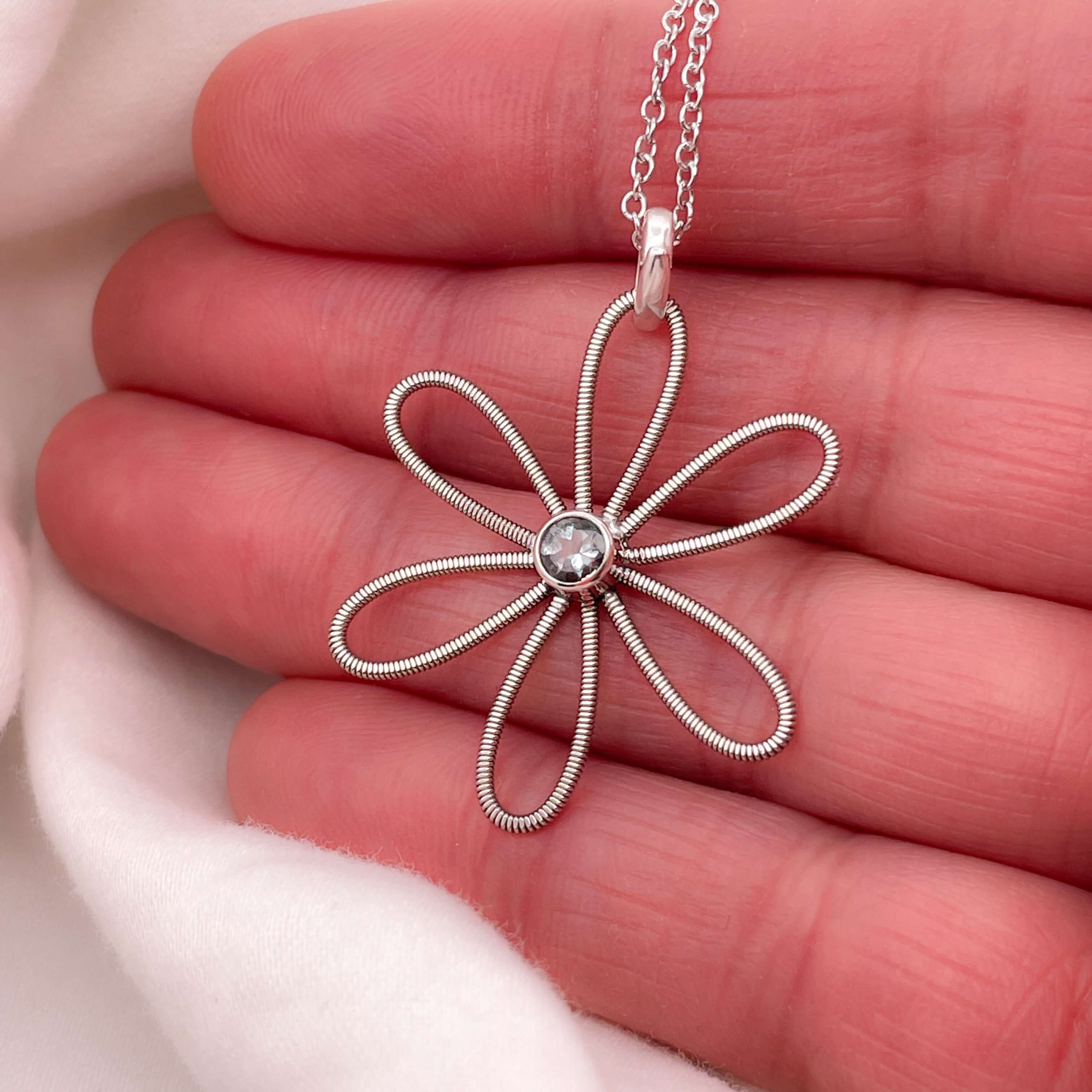 Electric guitar string flower with aquamarine at it's centre on a hand.