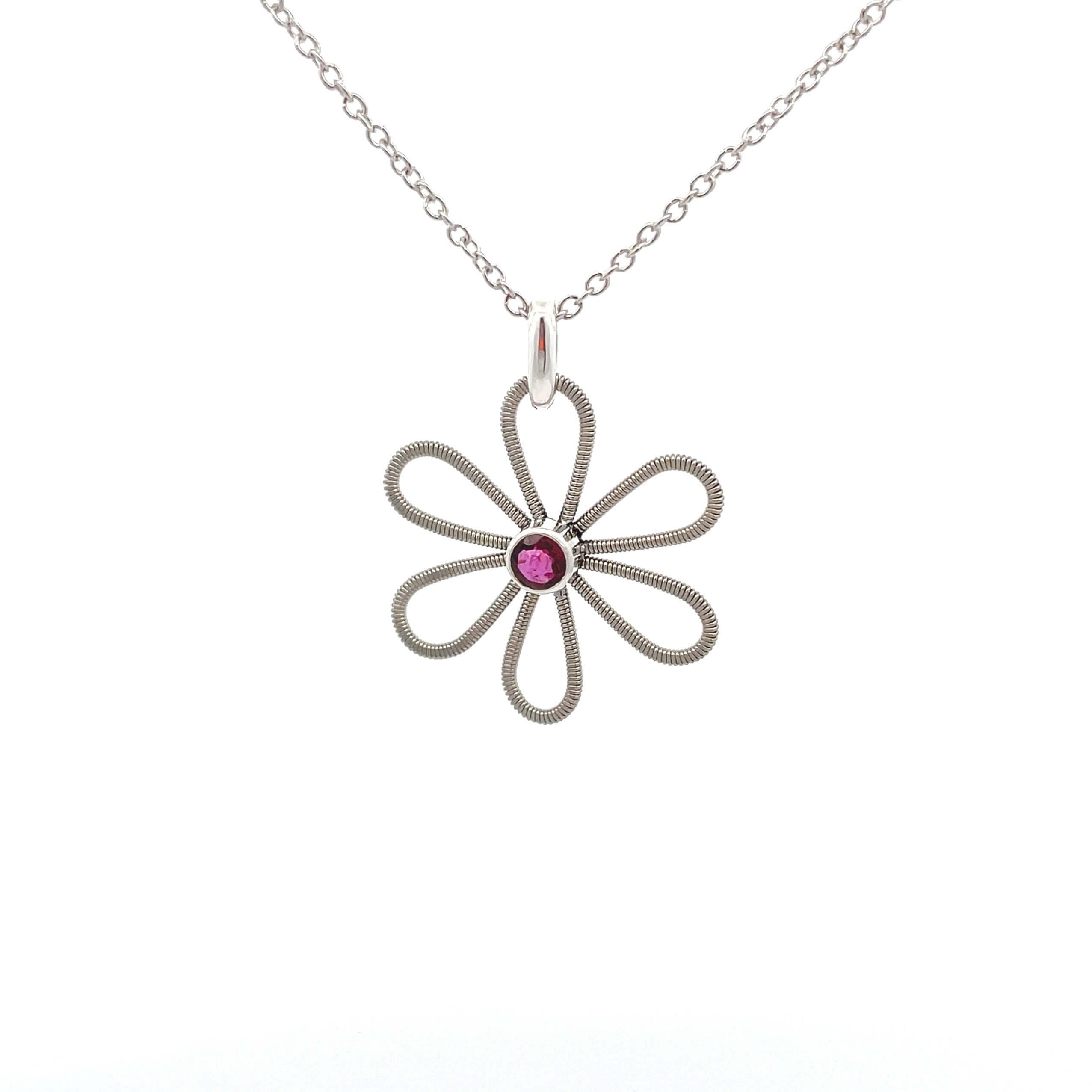 Electric guitar string flower pendant with garnet gemstone in the centre on a white background.