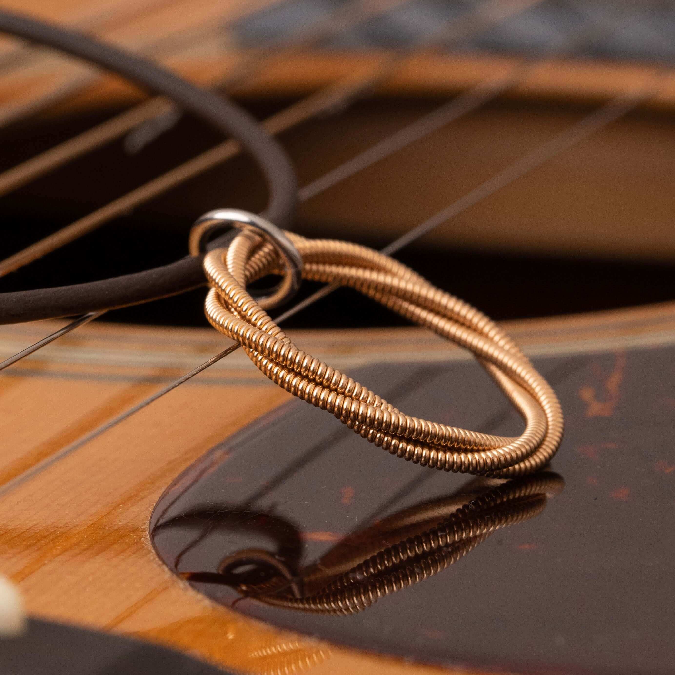 Twisted guitar string necklace on the surface of a guitar.