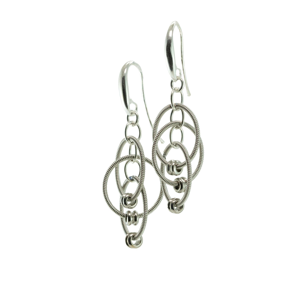 Multiple loop dangling reclaimed electric guitar string earrings with silver ear hooks on white background