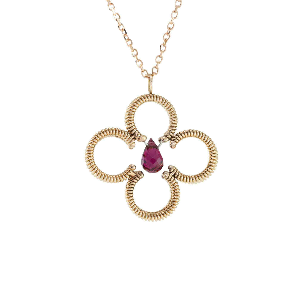 acoustic guitar string clover shaped pendant with a central red tourmaline gemstone with a rose gold chain on white background