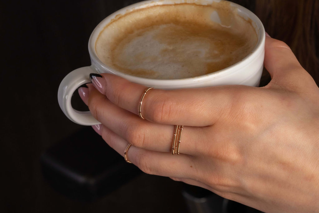 stacking duo guitar string rings on hand model holding coffee