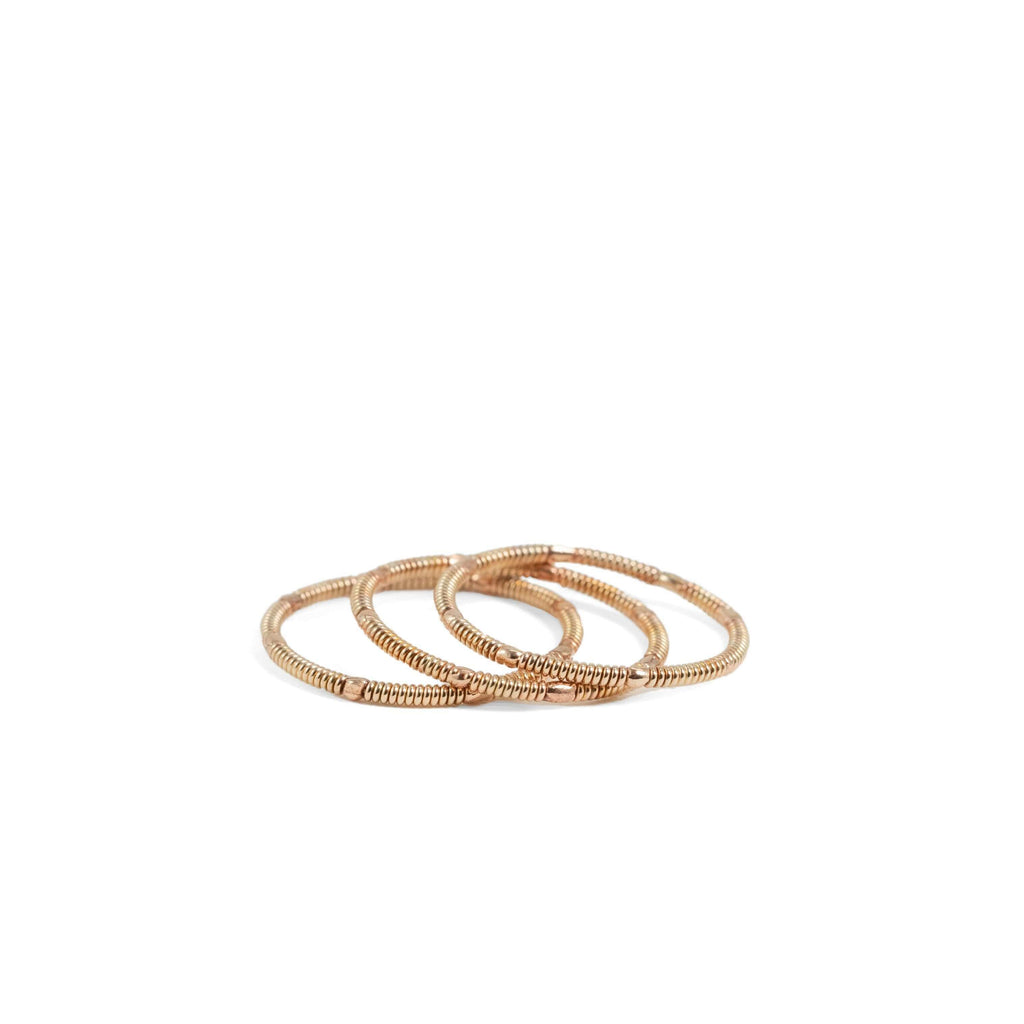three rose gold colored, stacking acoustic guitar string rings on white background