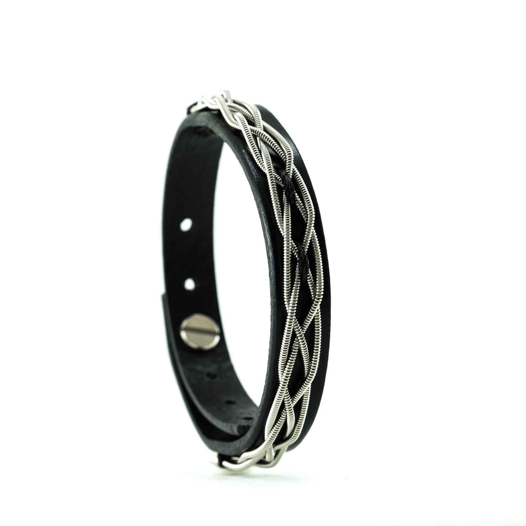 Woven electric guitar string and black leather bracelet on a white background, left view