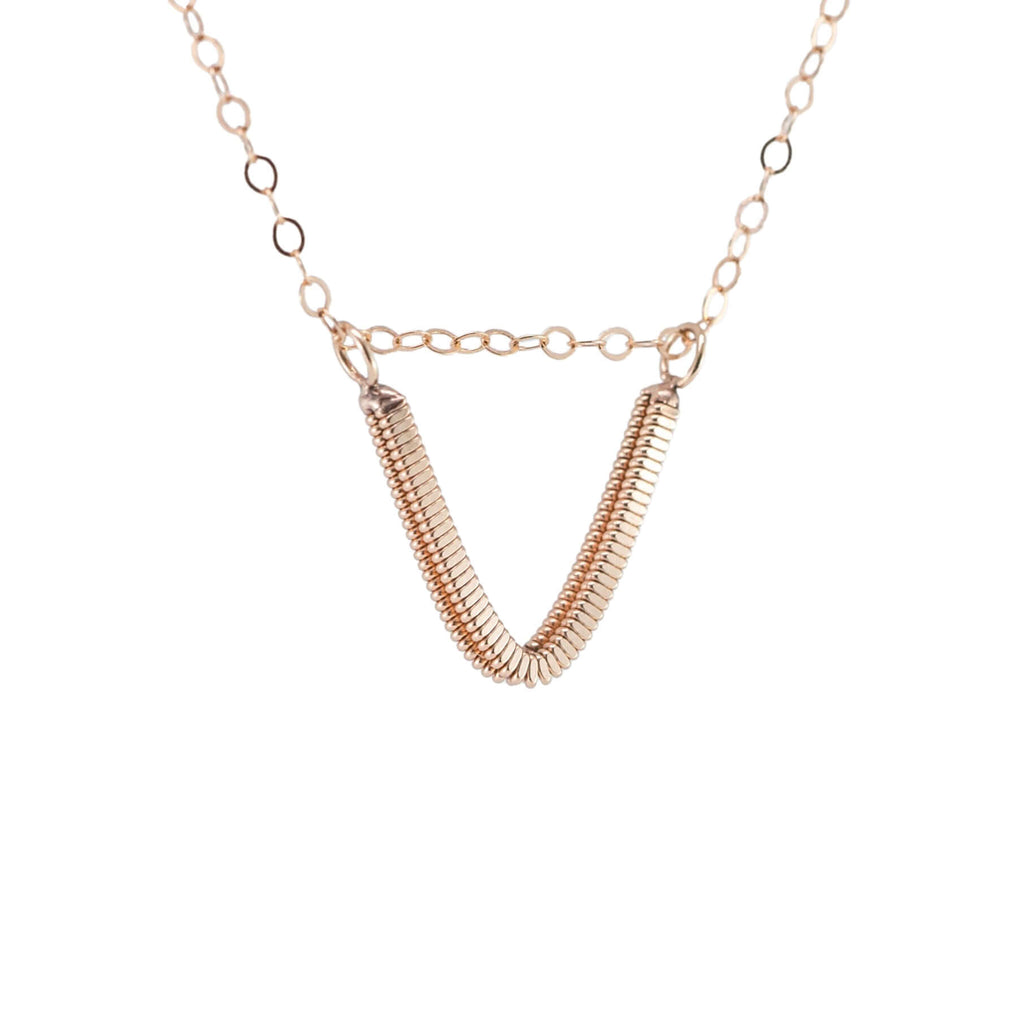 Rose gold guitar string v-necklace hanging with white background