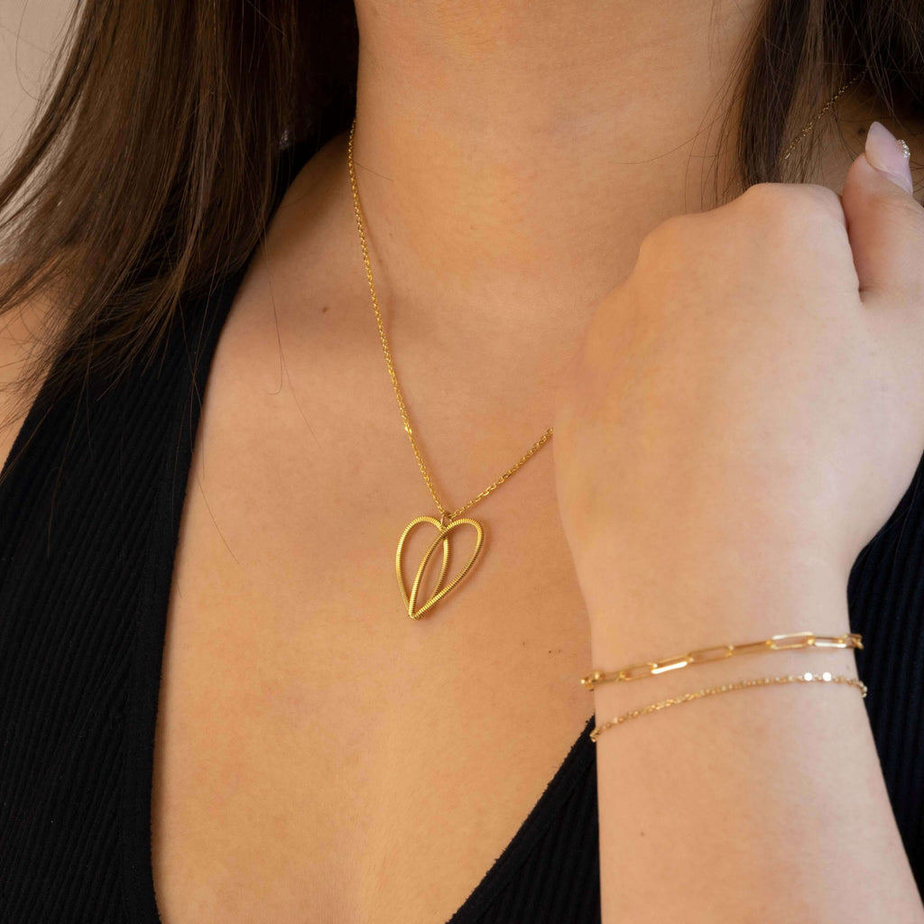 Gold guitar string heart on 10k gold chain on model with black top