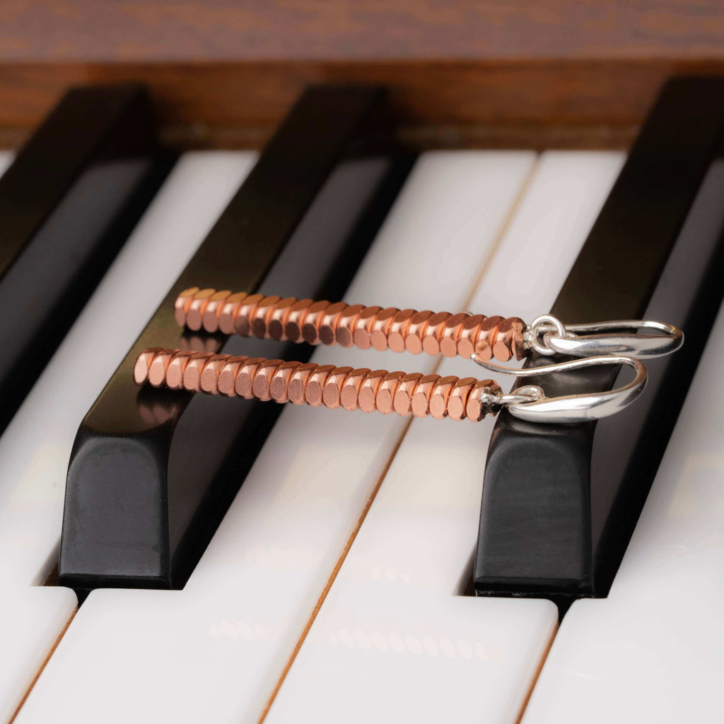 Piano bar earrings laying across piano keys