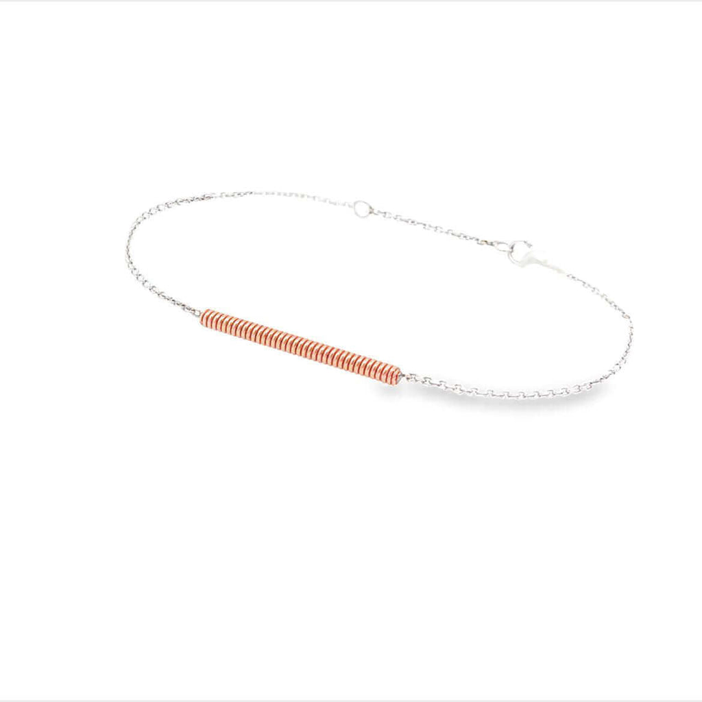 Piano string and white gold bracelet on a white background