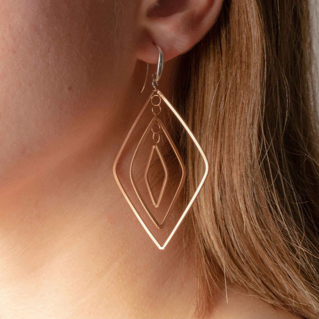 diamond-shaped dangle guitar string earrings on model