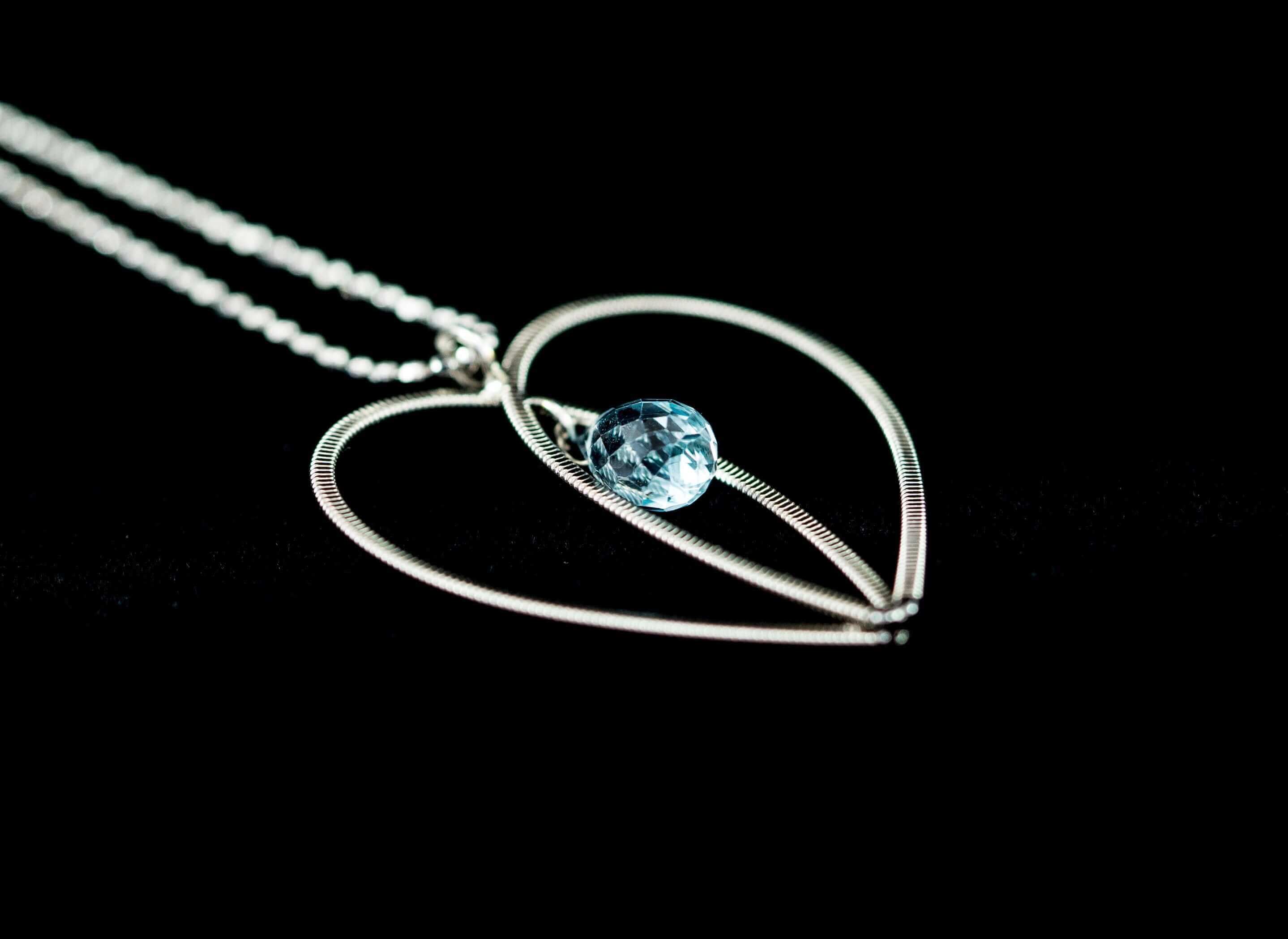 Guitar string heart necklace with aquamarine gemstone on black background