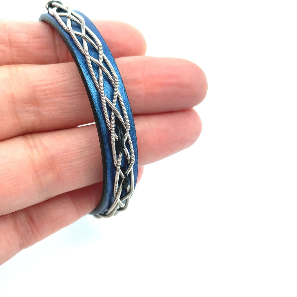 Blue leather electric guitar string bracelet on hand for size reference