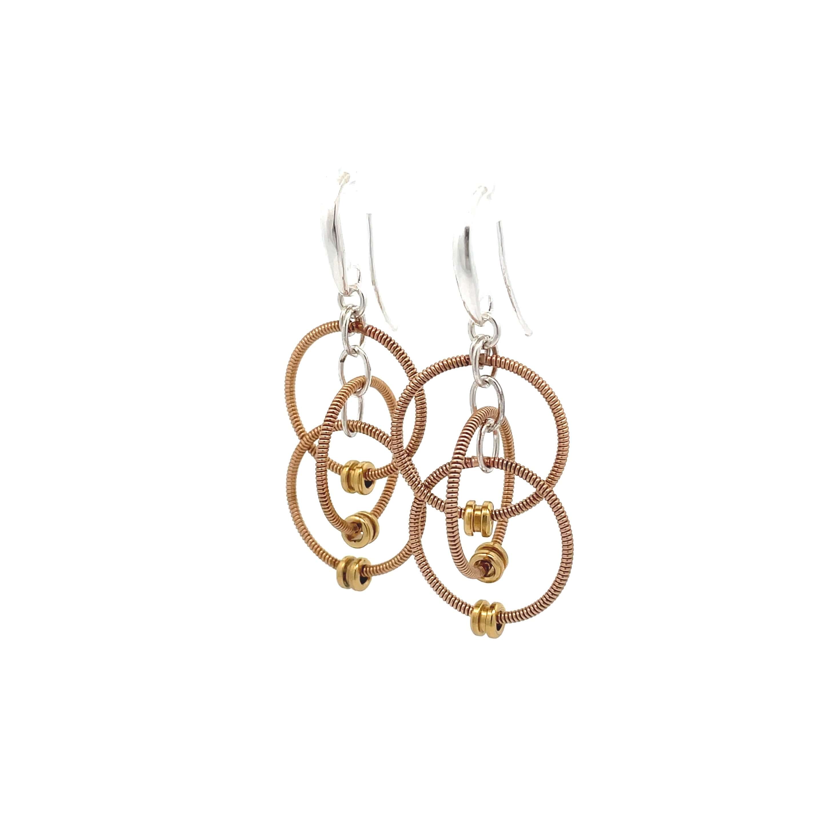 Multiple loop dangling reclaimed guitar string earrings with silver ear hooks on white background