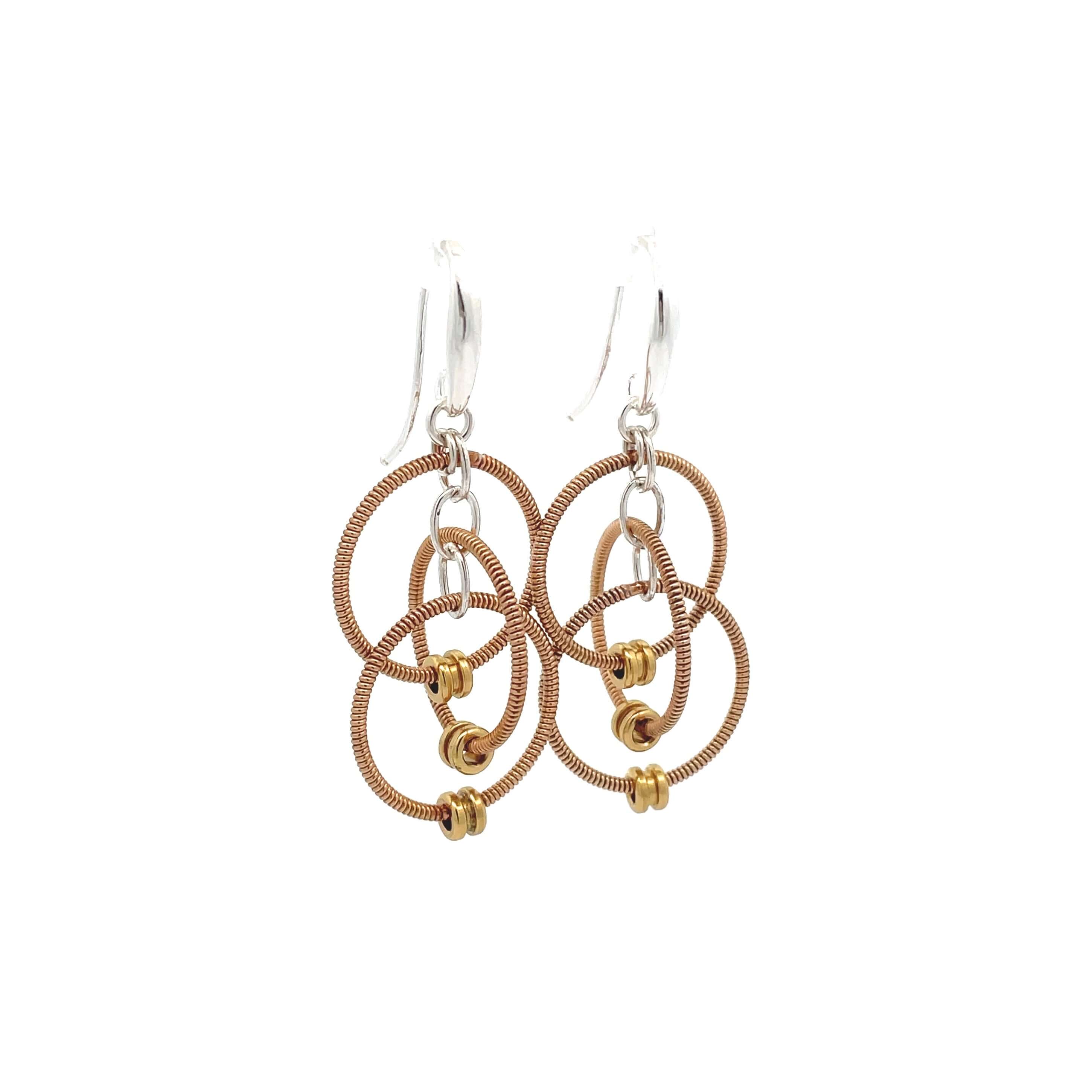 Multiple loop dangling reclaimed guitar string earrings with silver ear hooks on white background