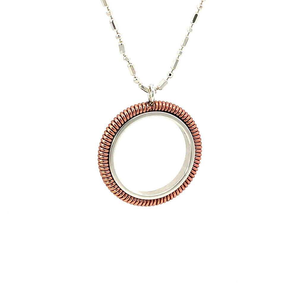 Piano string ring necklace hanging on white background