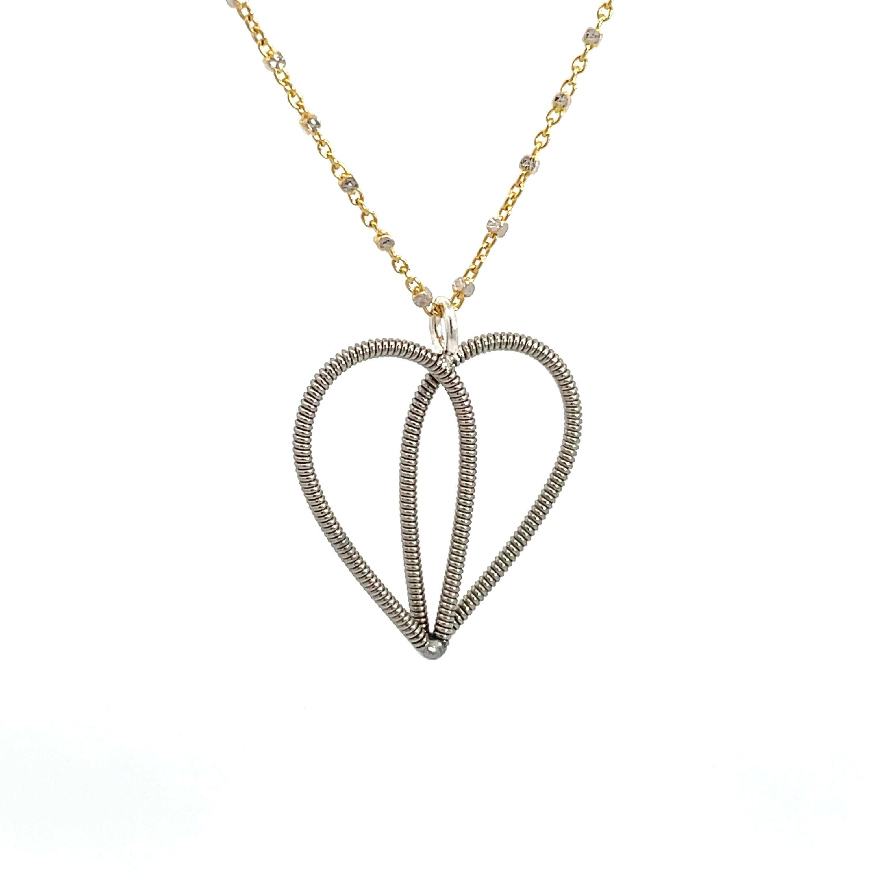 Guitar string heart on a gold and white gold chain on a white background