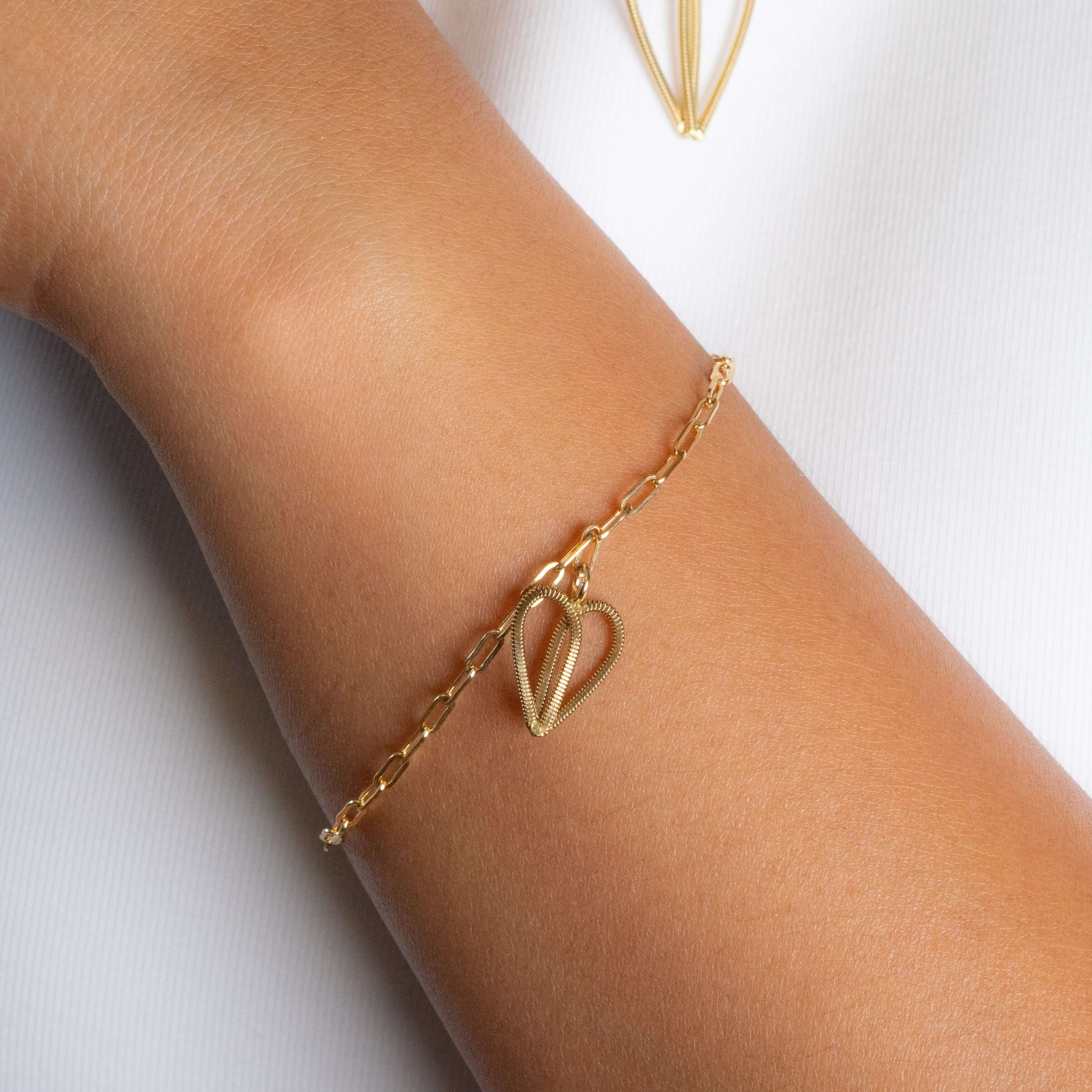 Silver guitar string bracelet on paperclip chain on model.