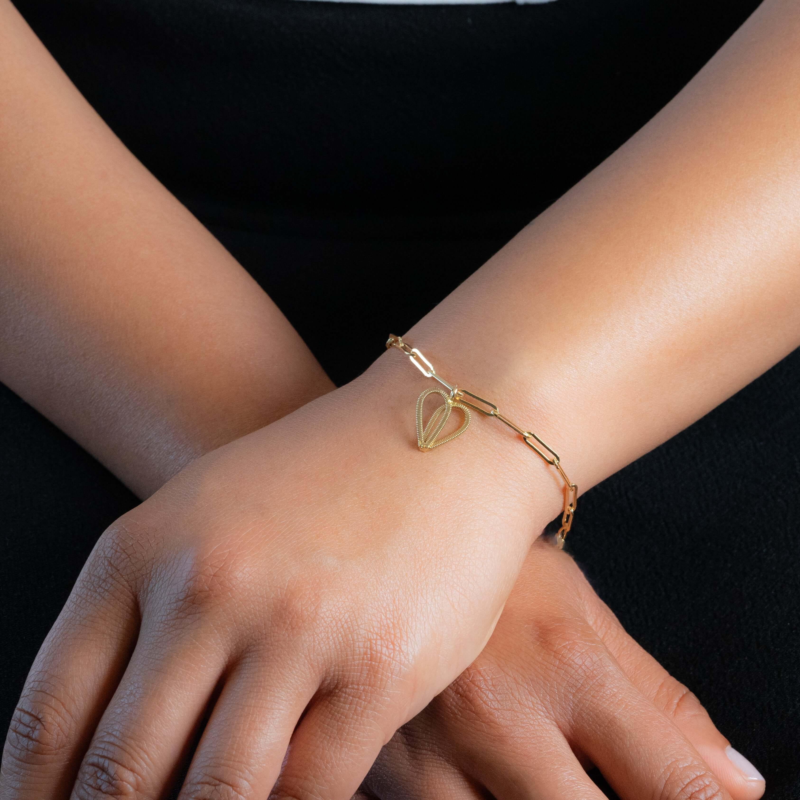 Silver guitar string bracelet on paperclip chain on model.