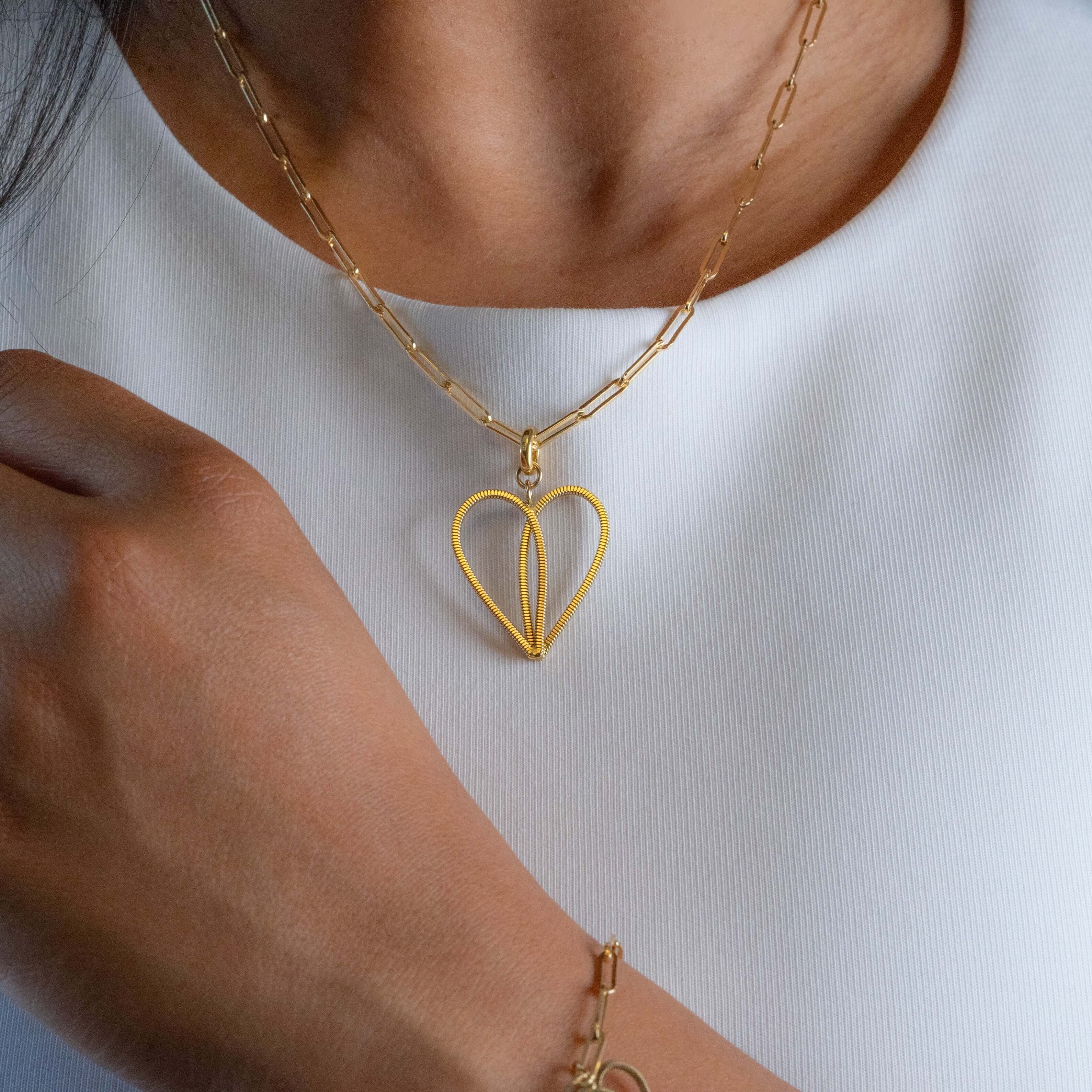 Gold guitar string necklace on model with white top.
