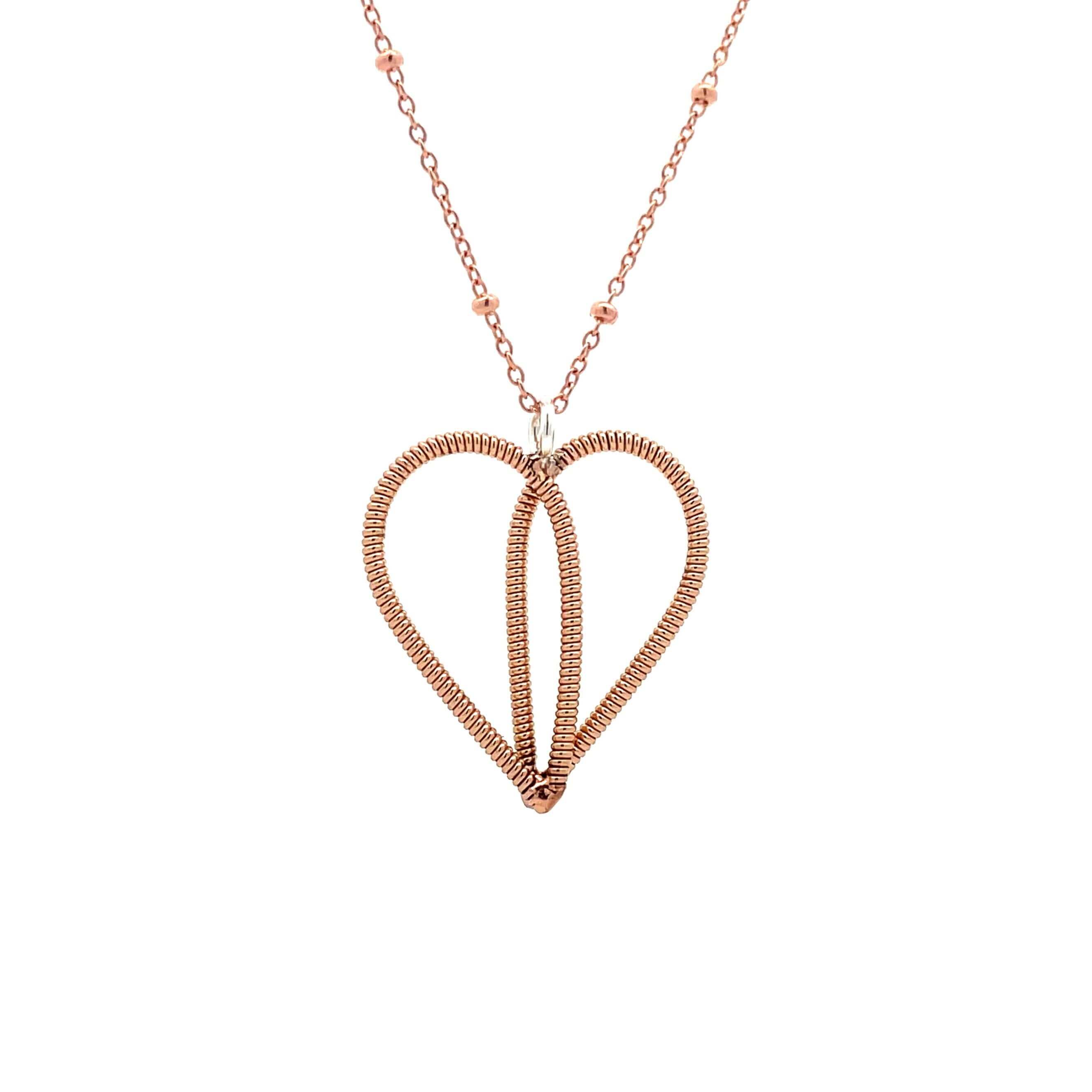 Bronze guitar string heart on rose gold chain with white background.