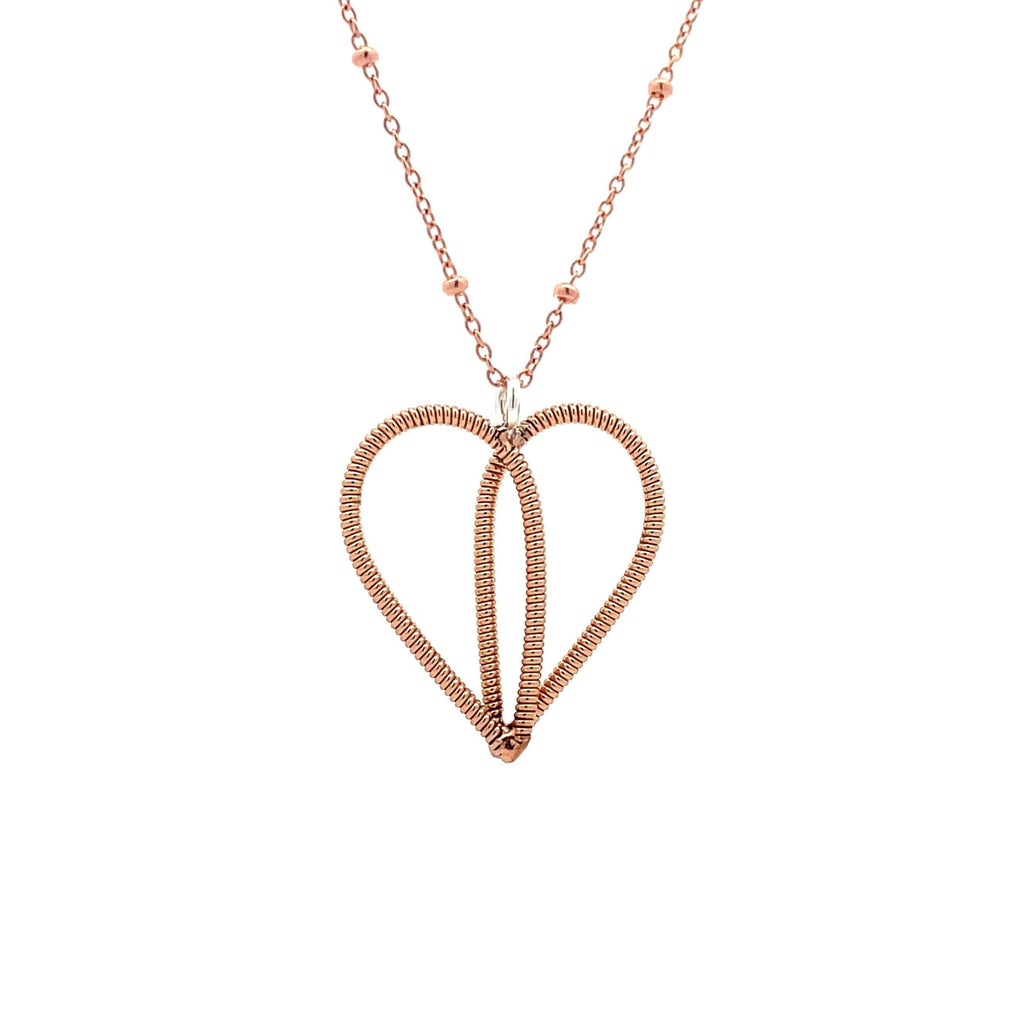 Bronze guitar string heart on rose gold chain with white background.