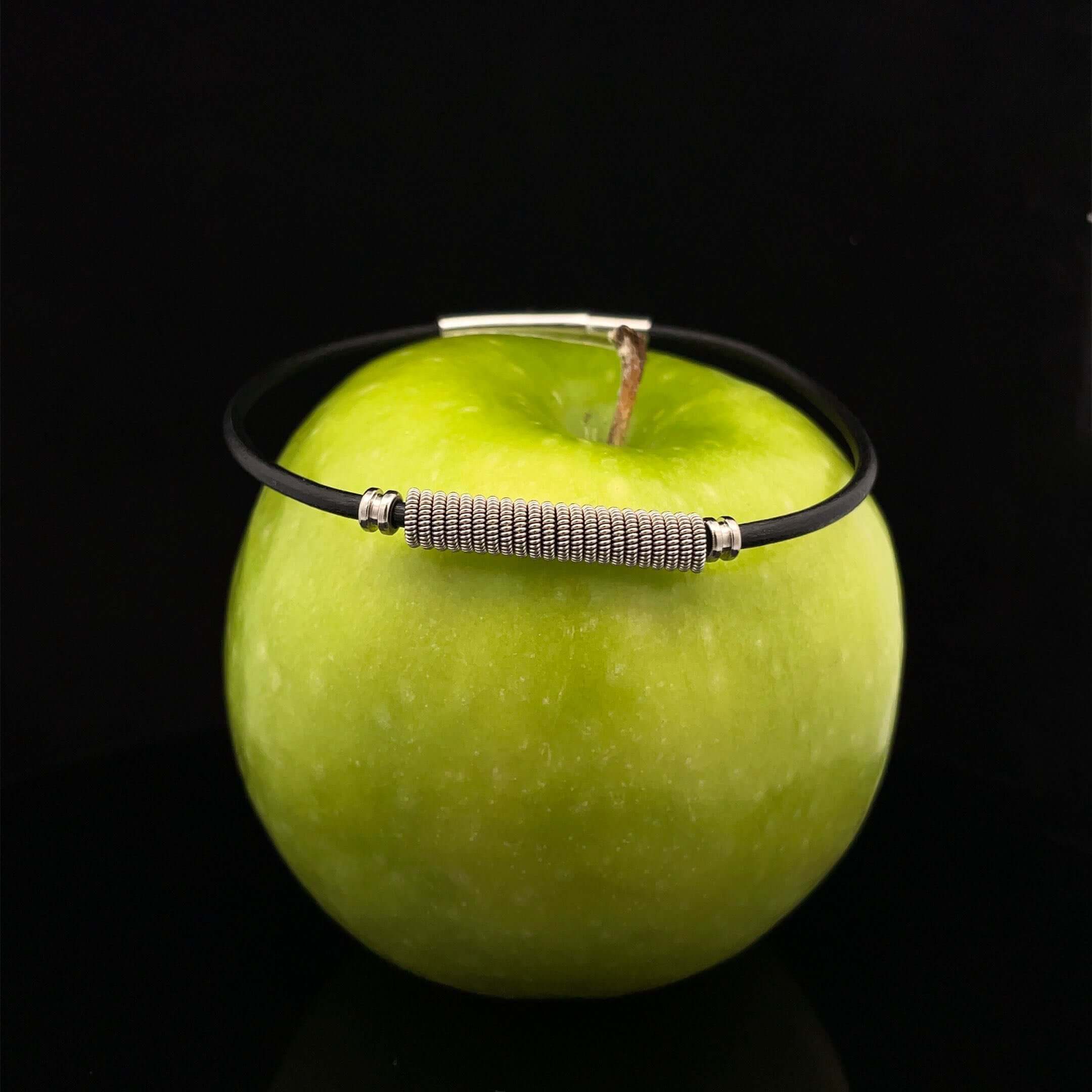 black guitar string bracelet on green apple with black background