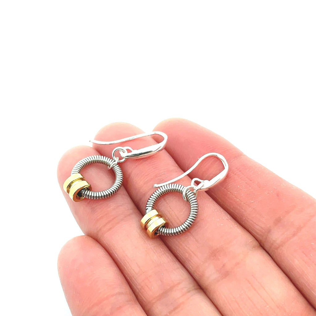 Bass guitar string earrings with brass ball ends on hand