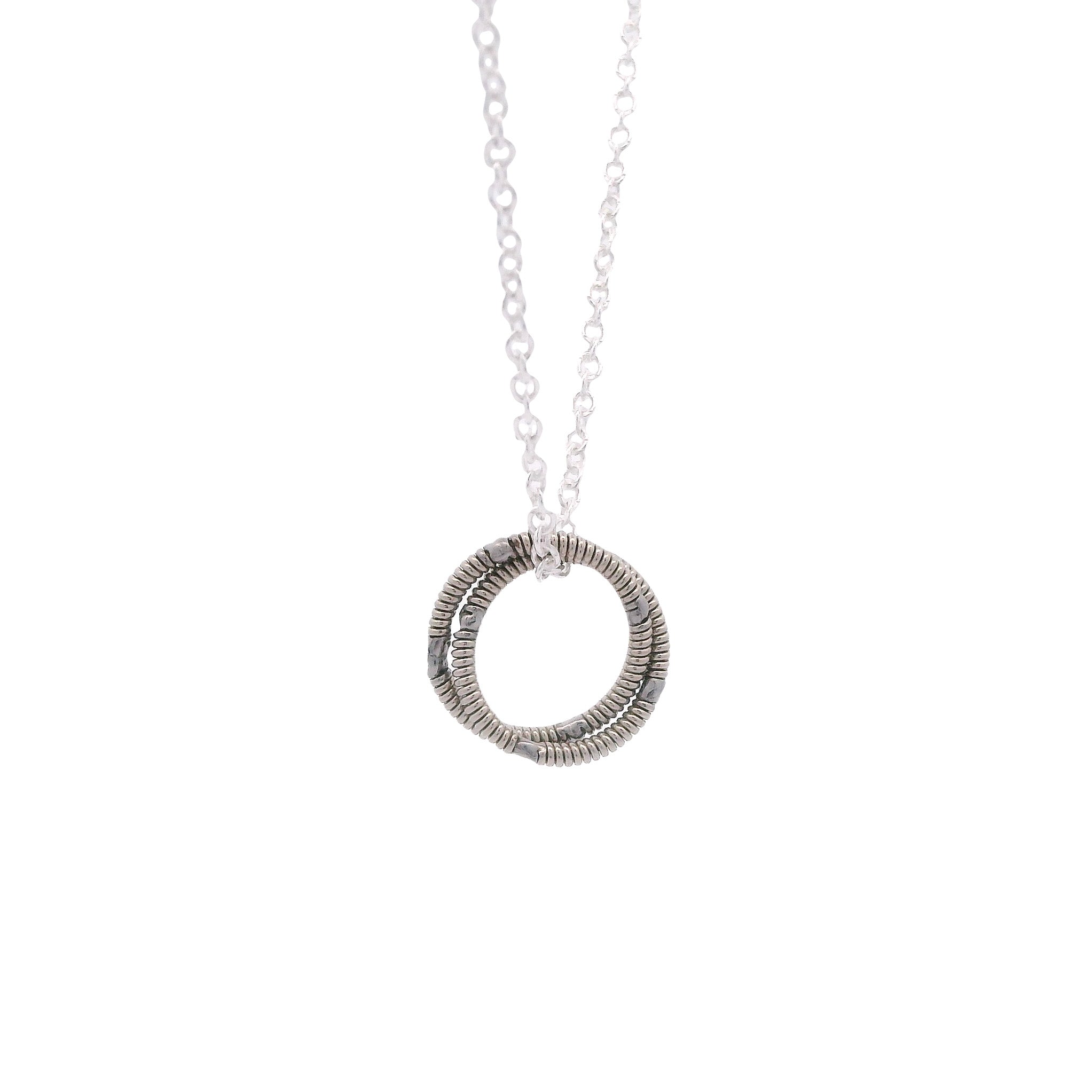 Silver circular guitar string pendant necklace on a white background