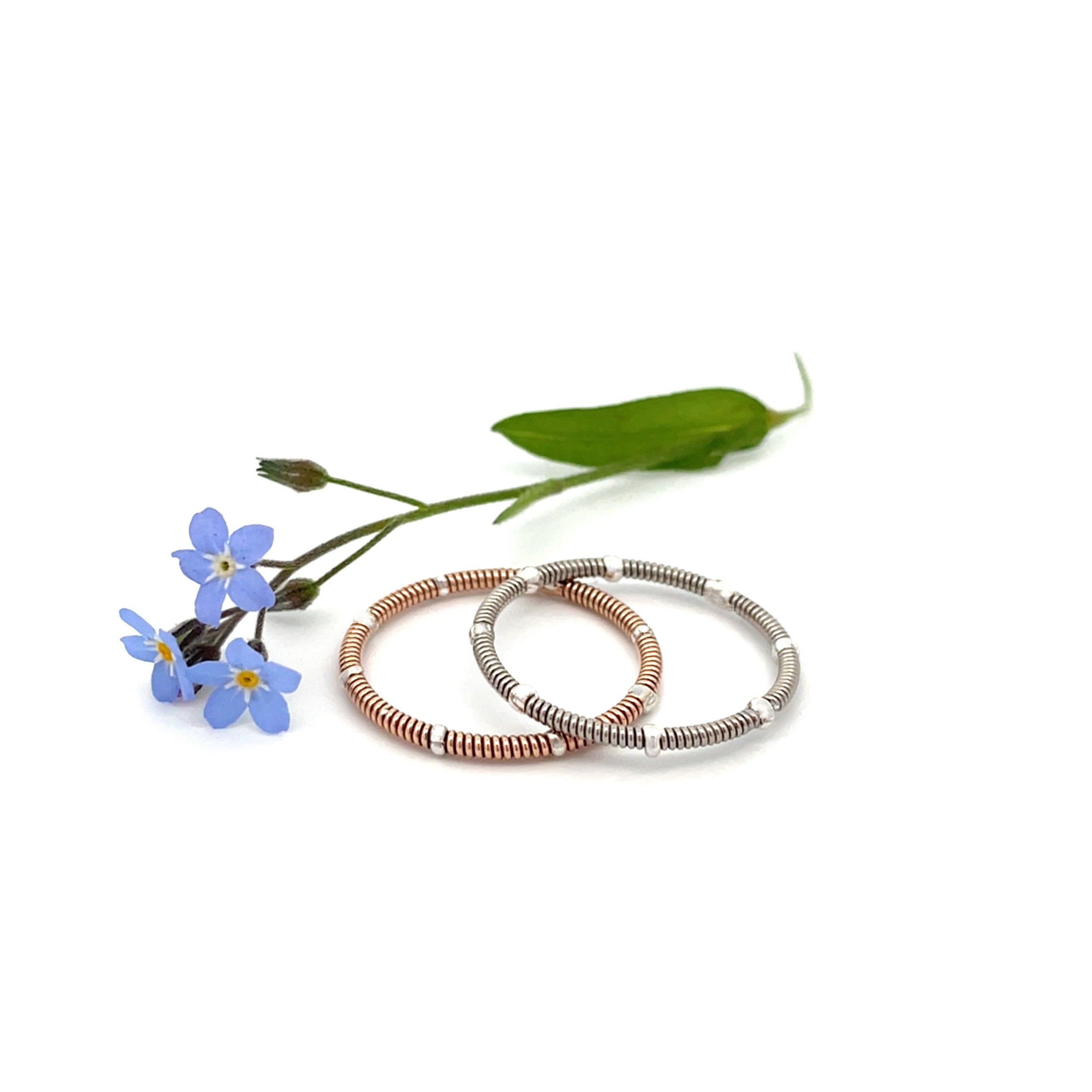 two guitar string rings on white background with blue flower