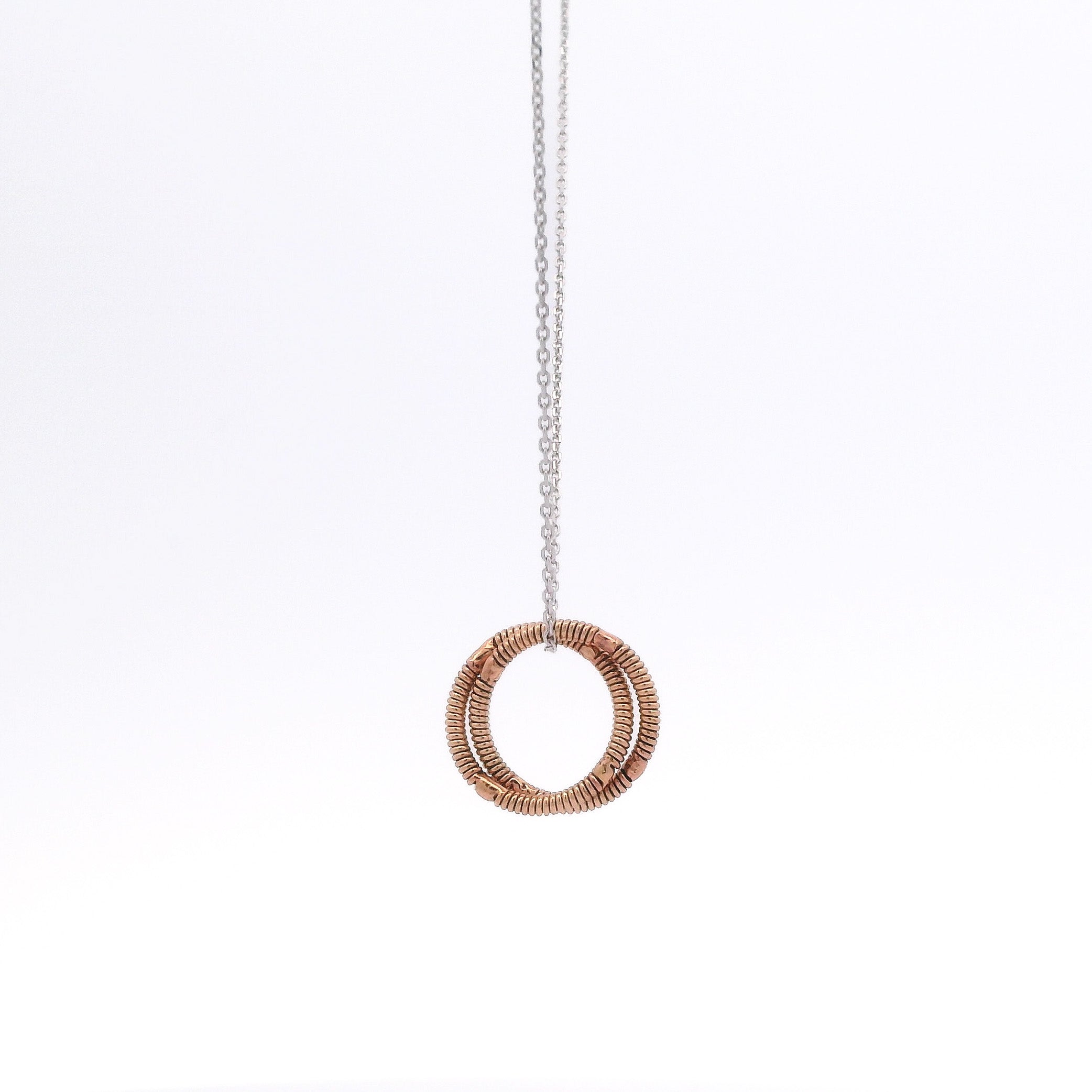 Necklace with a circular guitar string pendant on a white background