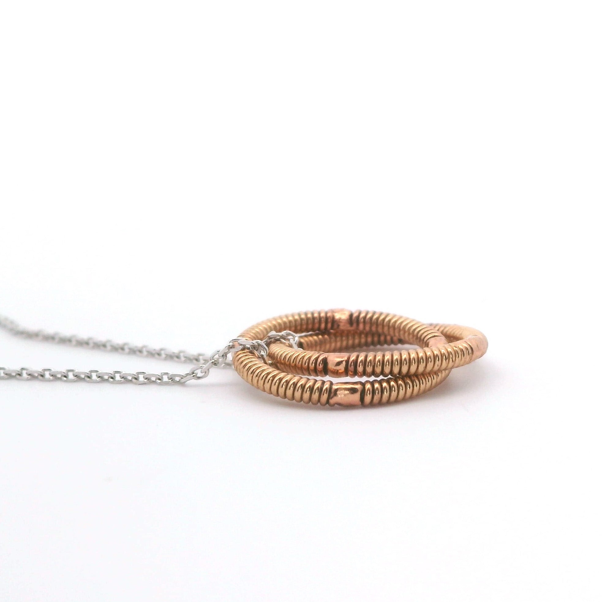 Necklace with two interlocking guitar string rings on a white background
