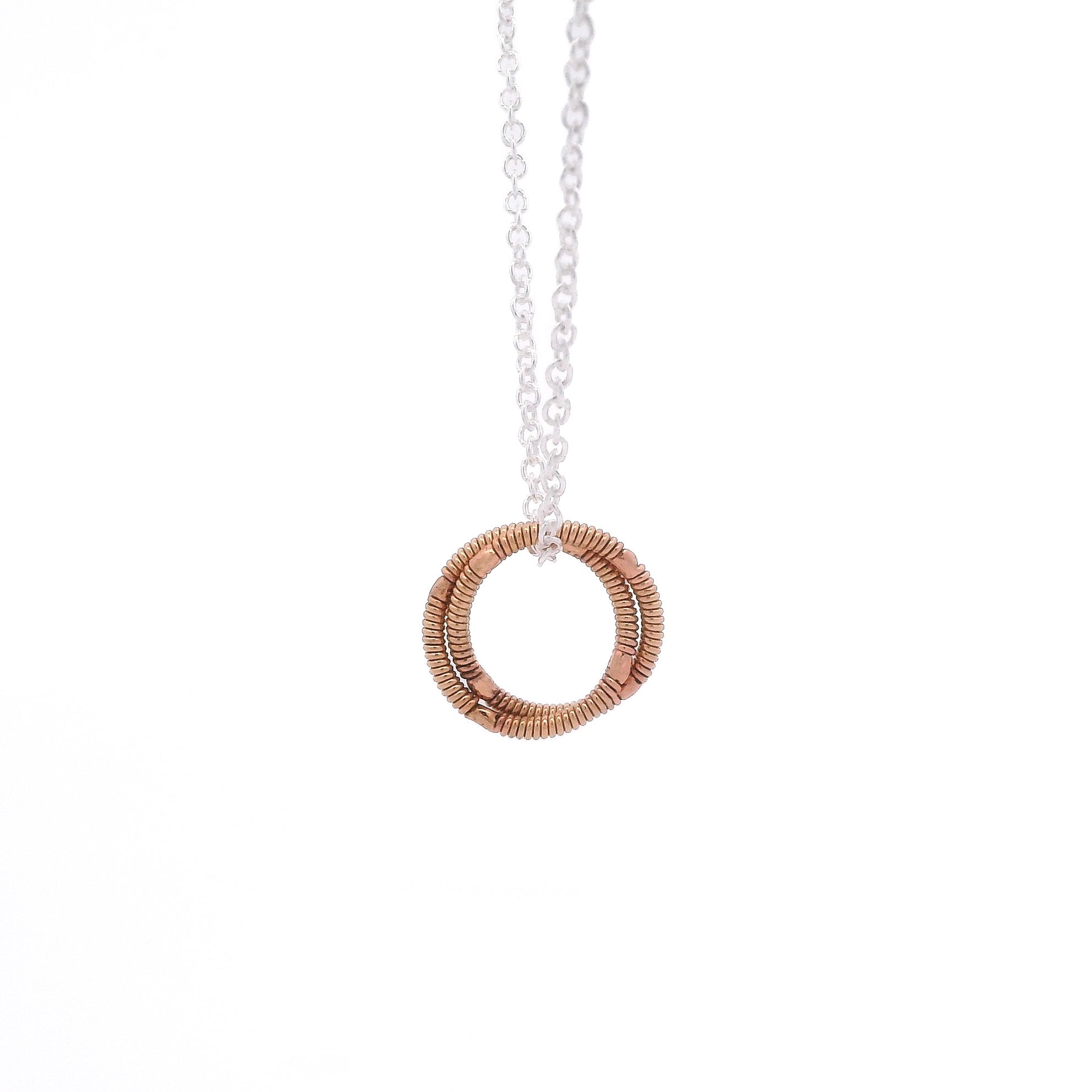Necklace with a guitar string circular pendant on a white background