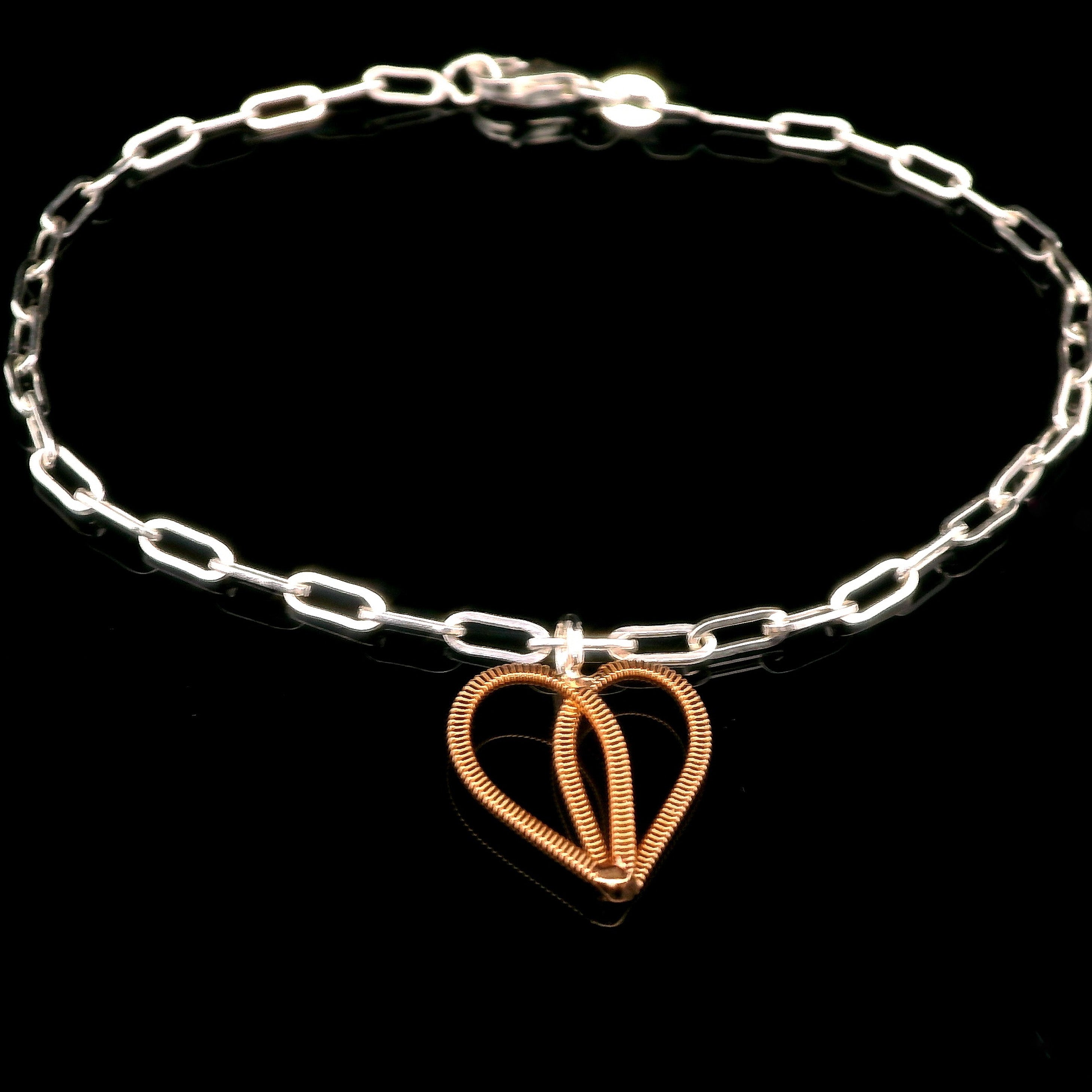 guitar string heart and silver bracelet on black background