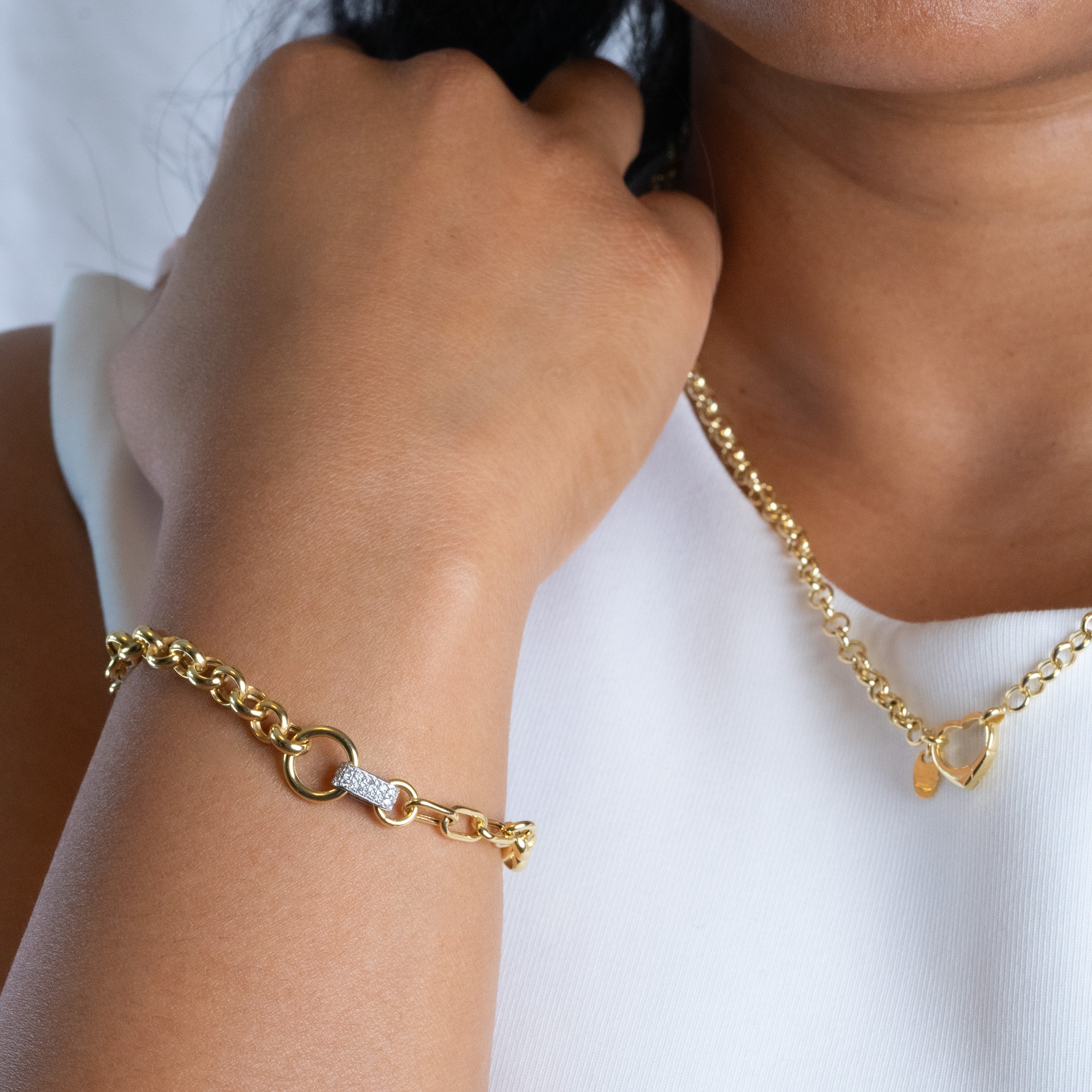 Gold bracelet and necklace on a person wearing a white top