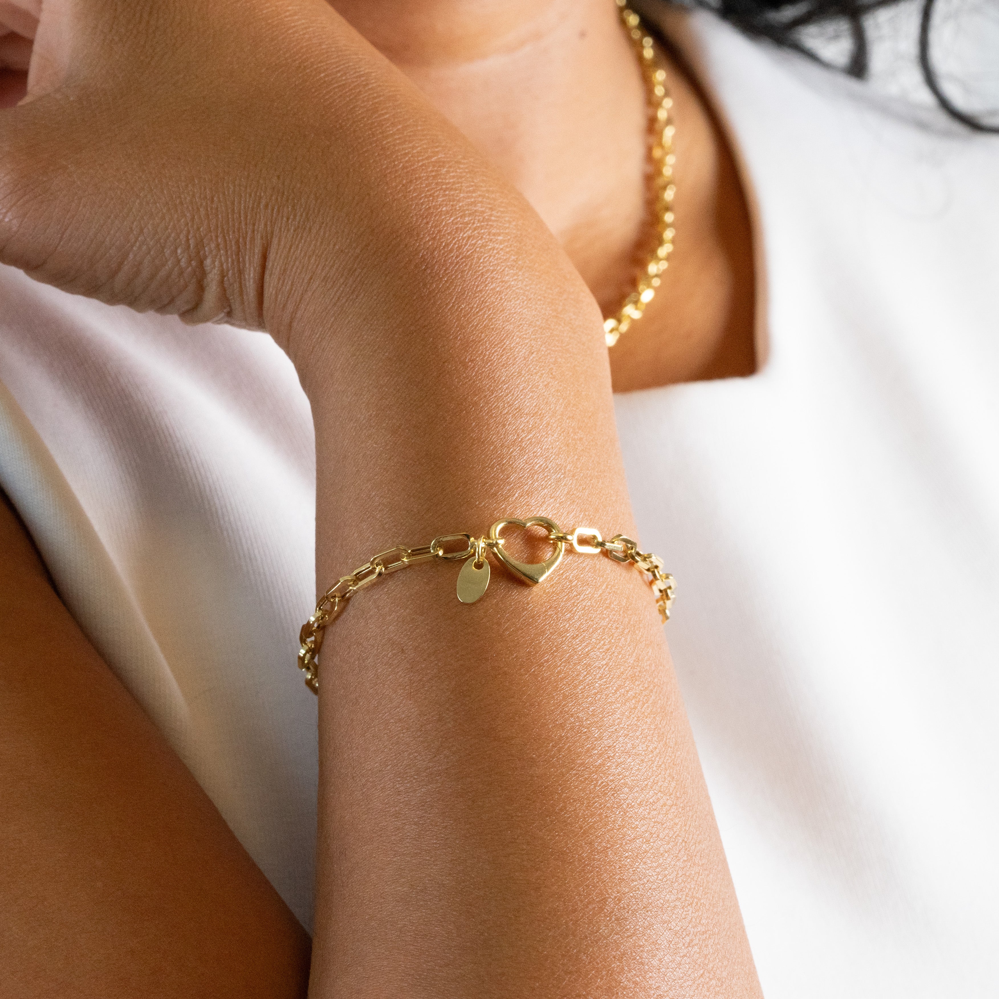 Gold bracelet on a person's wrist with a white background