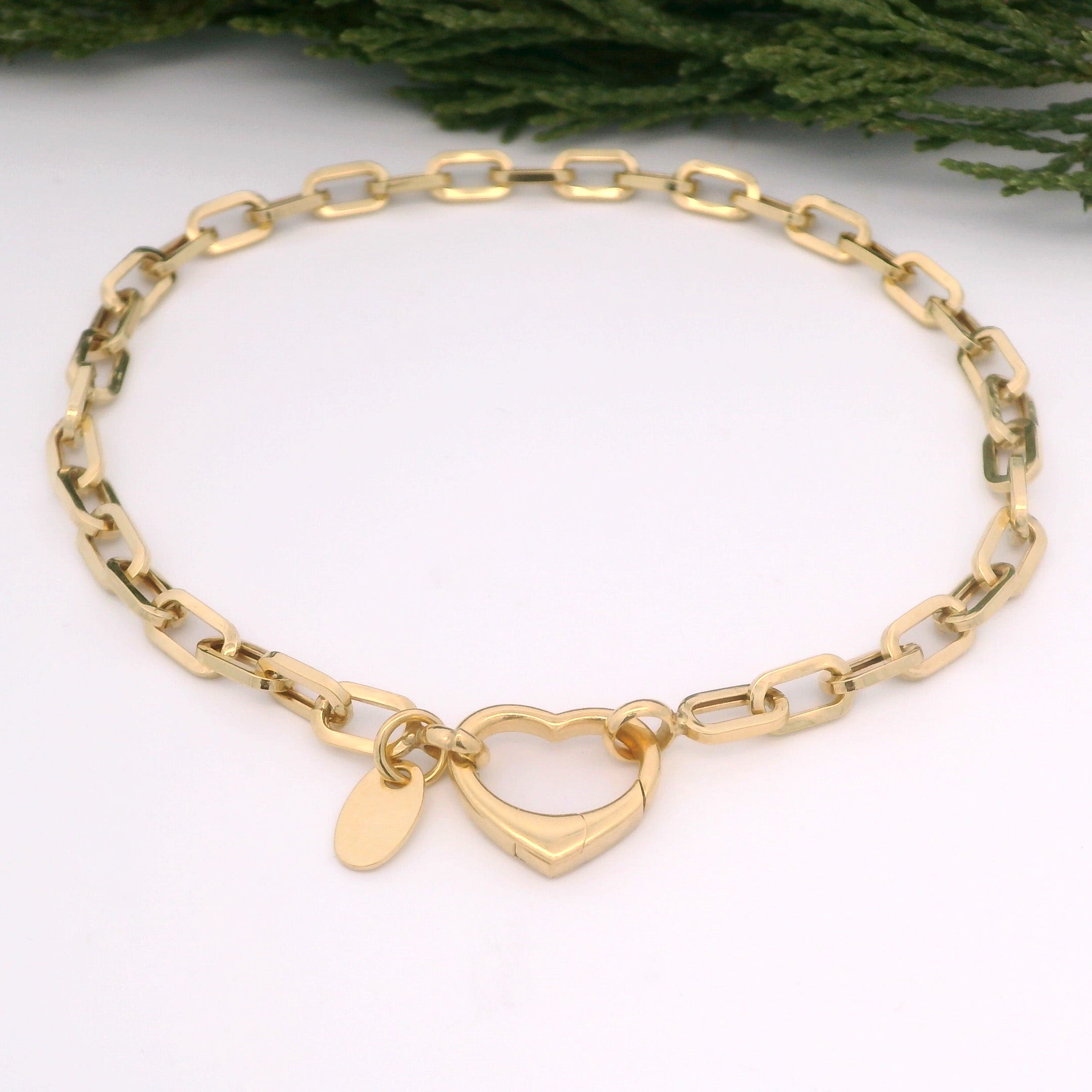 Gold bracelet with a heart-shaped charm on a white background