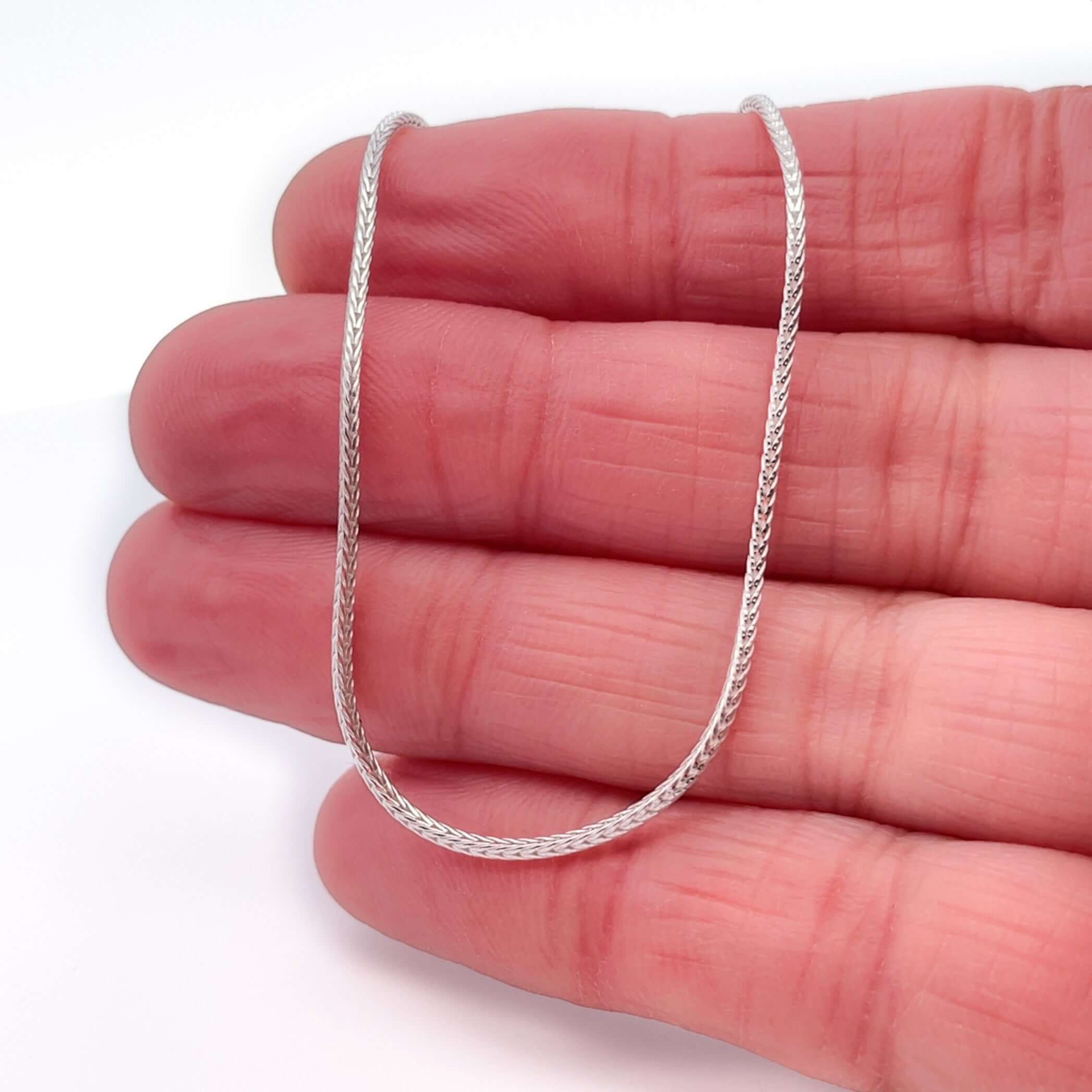 Silver foxtail chain on hand with white background