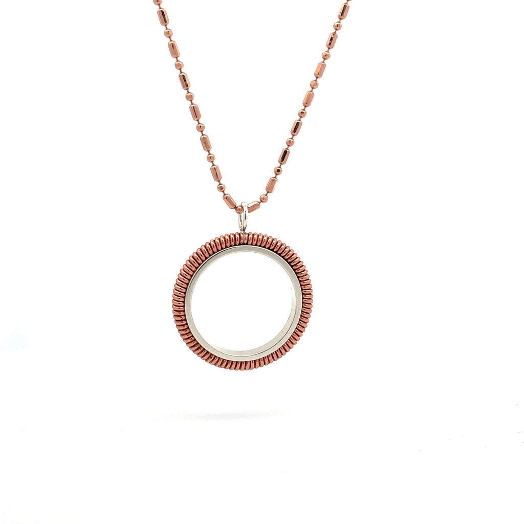 Piano string ring necklace with rose chain hanging on white background