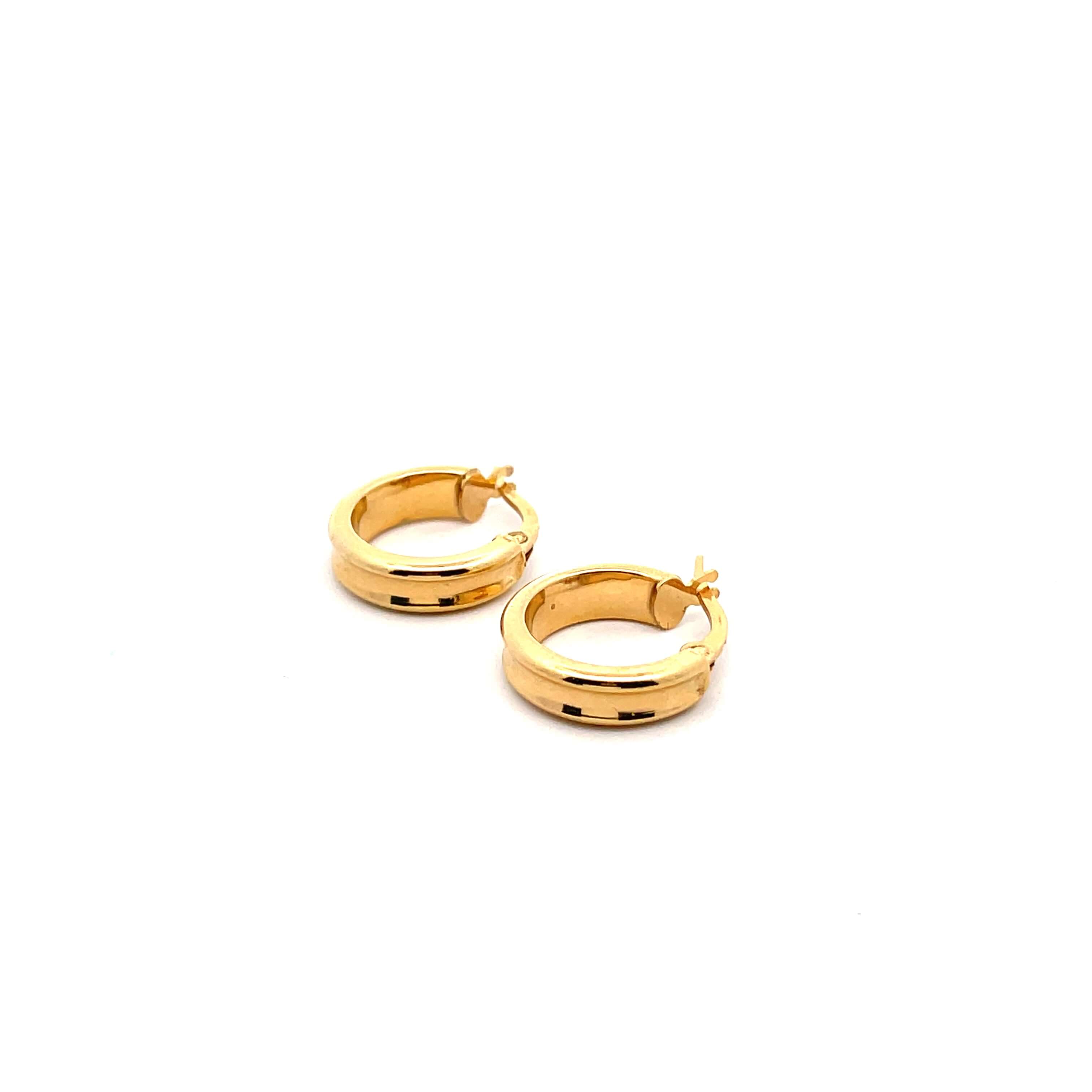 Gold hoop earrings with groove on white background