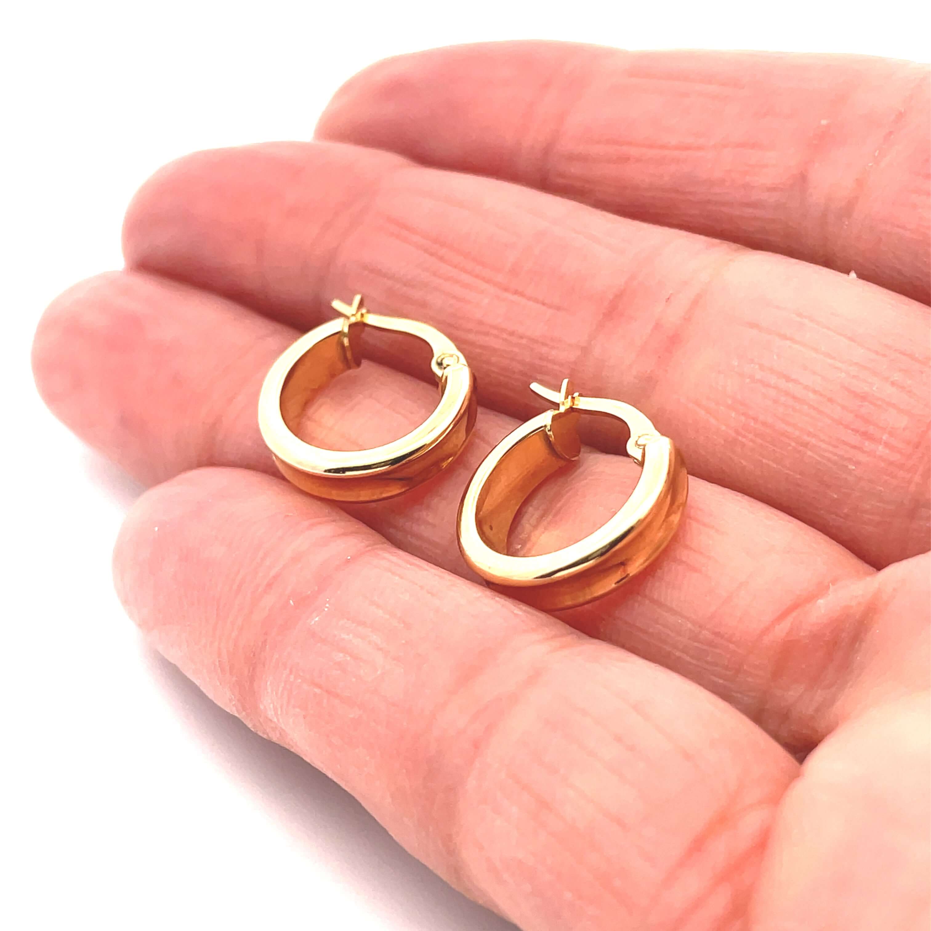 Gold hoop earrings with groove on a hand