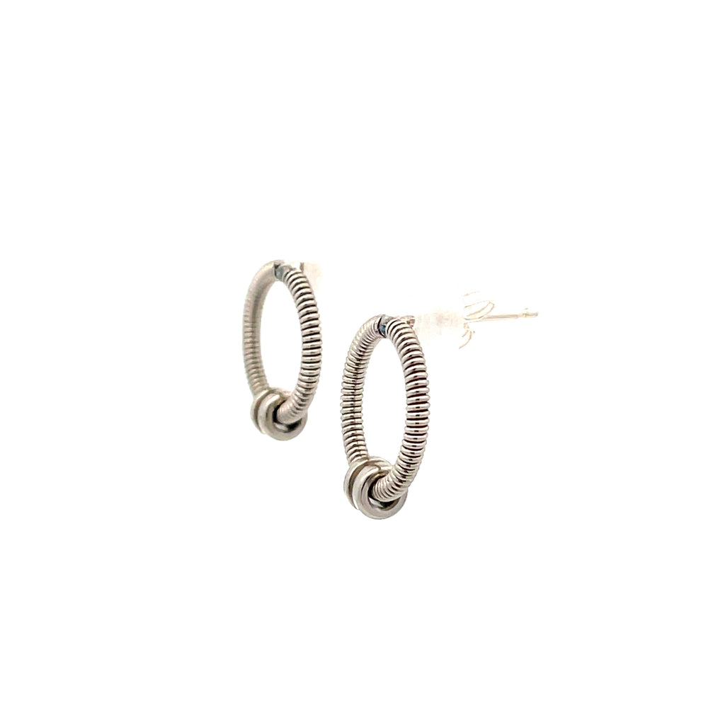Bass guitar string earrings with guitar string ball ends hanging on white background, side view