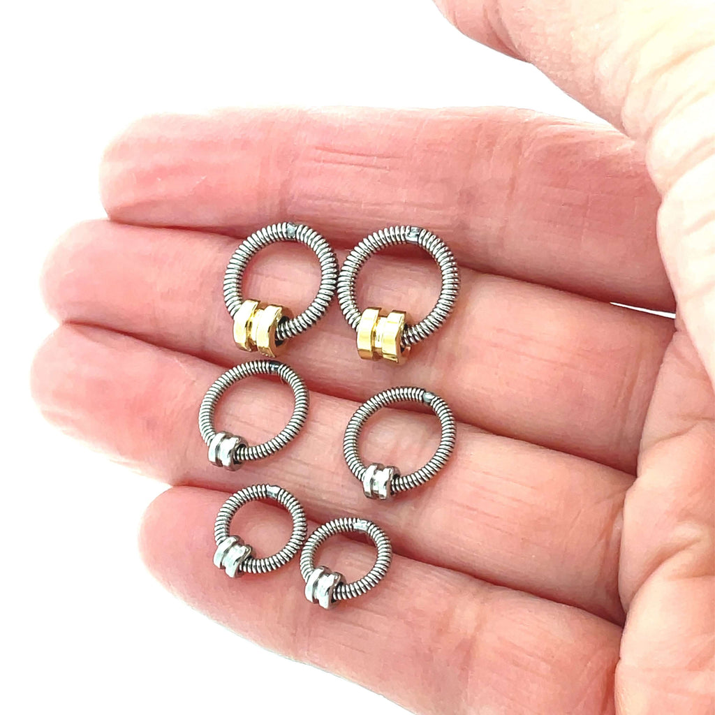 3 sets of bass guitar string earrings on a hand