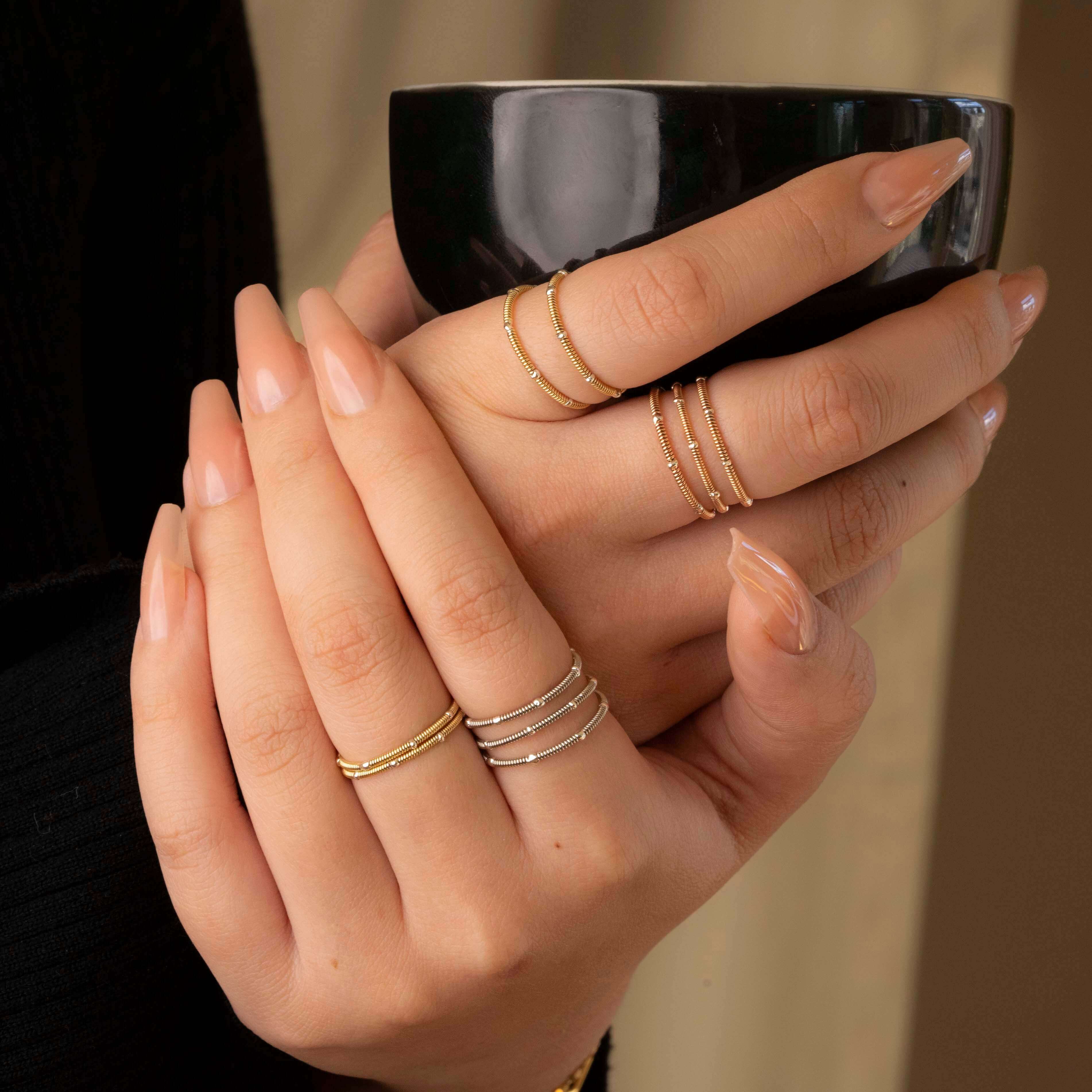 Guitar string stacking rings on model holding black coffee cup