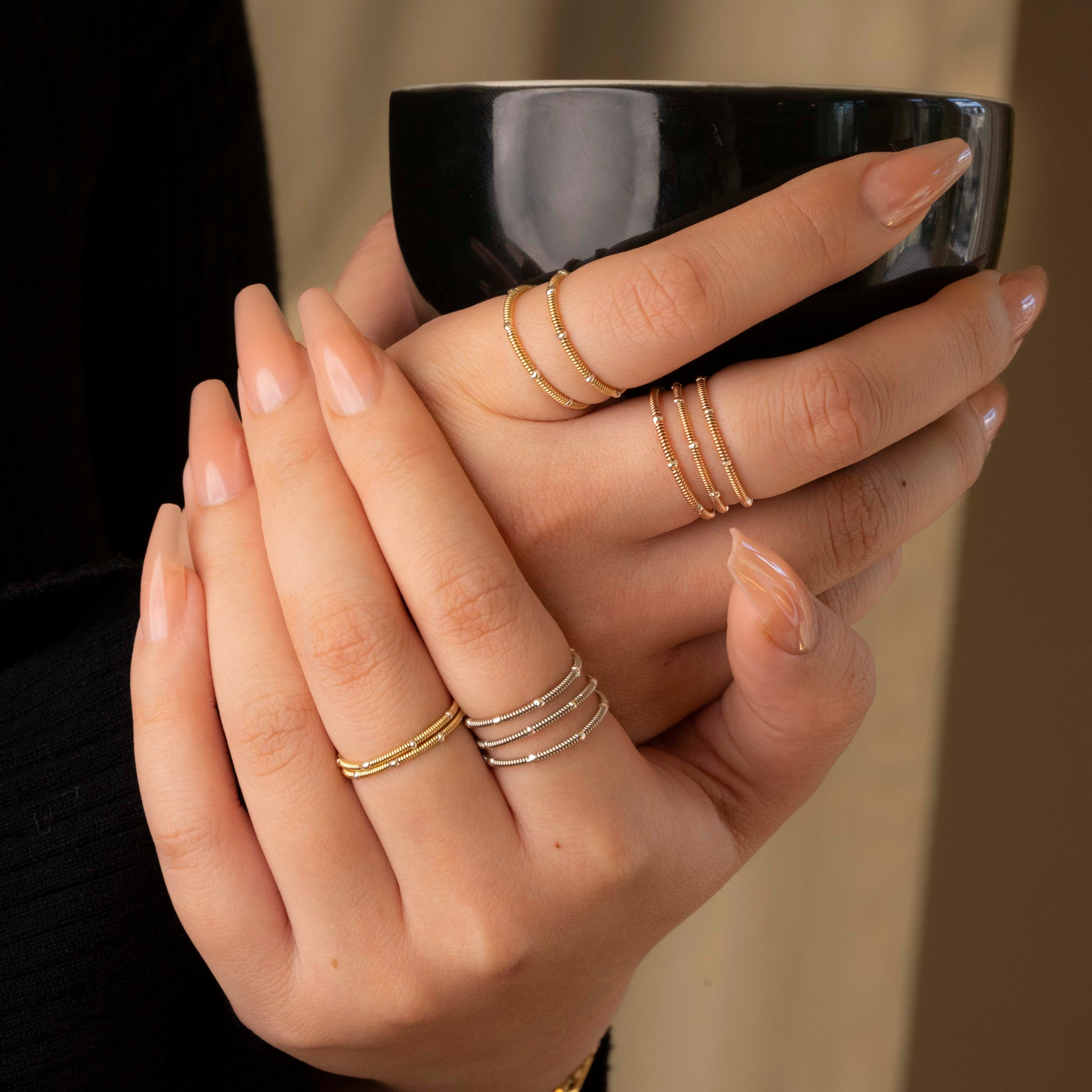 girl wearing rings and holding white coffee cup