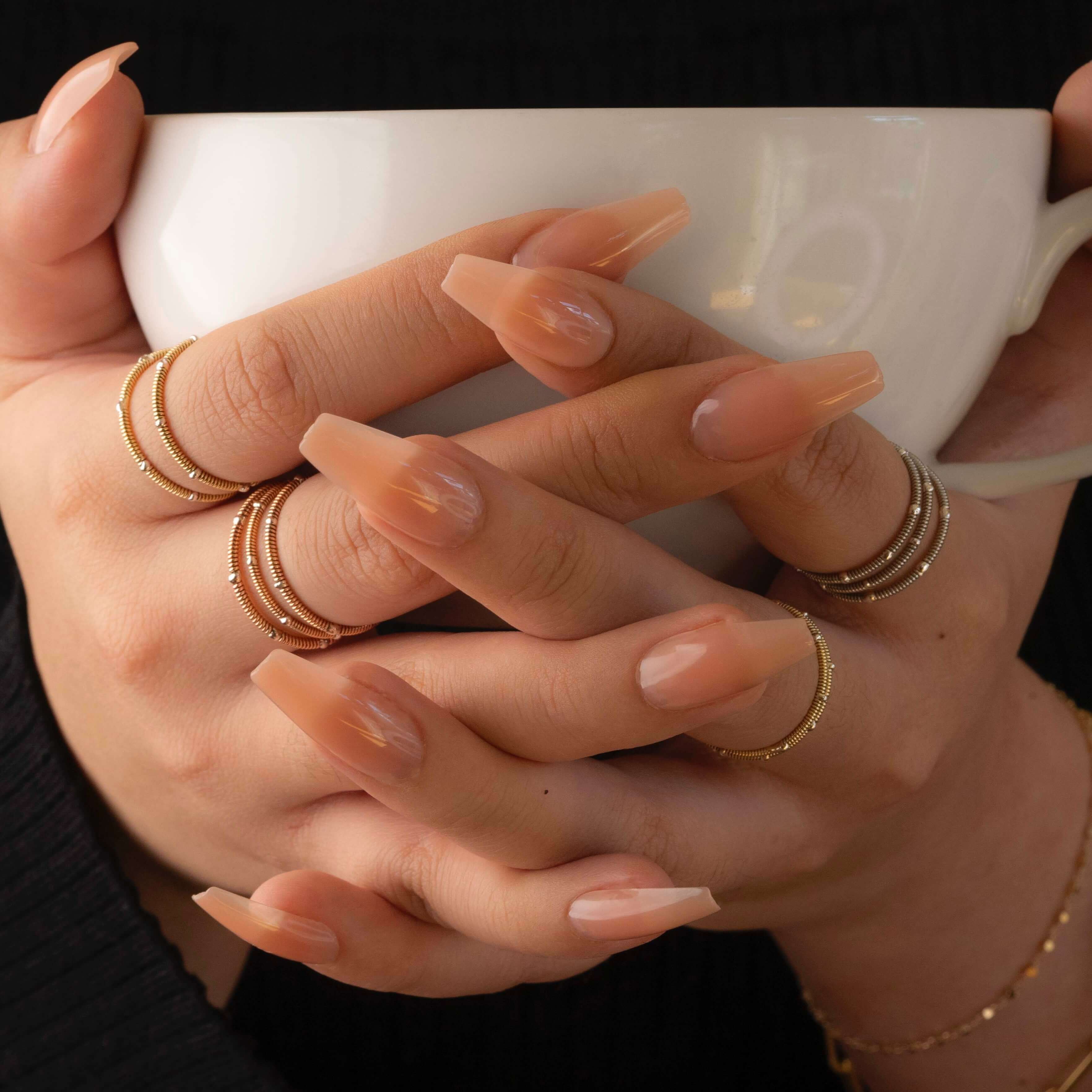 Guitar string stacking rings on model holding white coffee cup