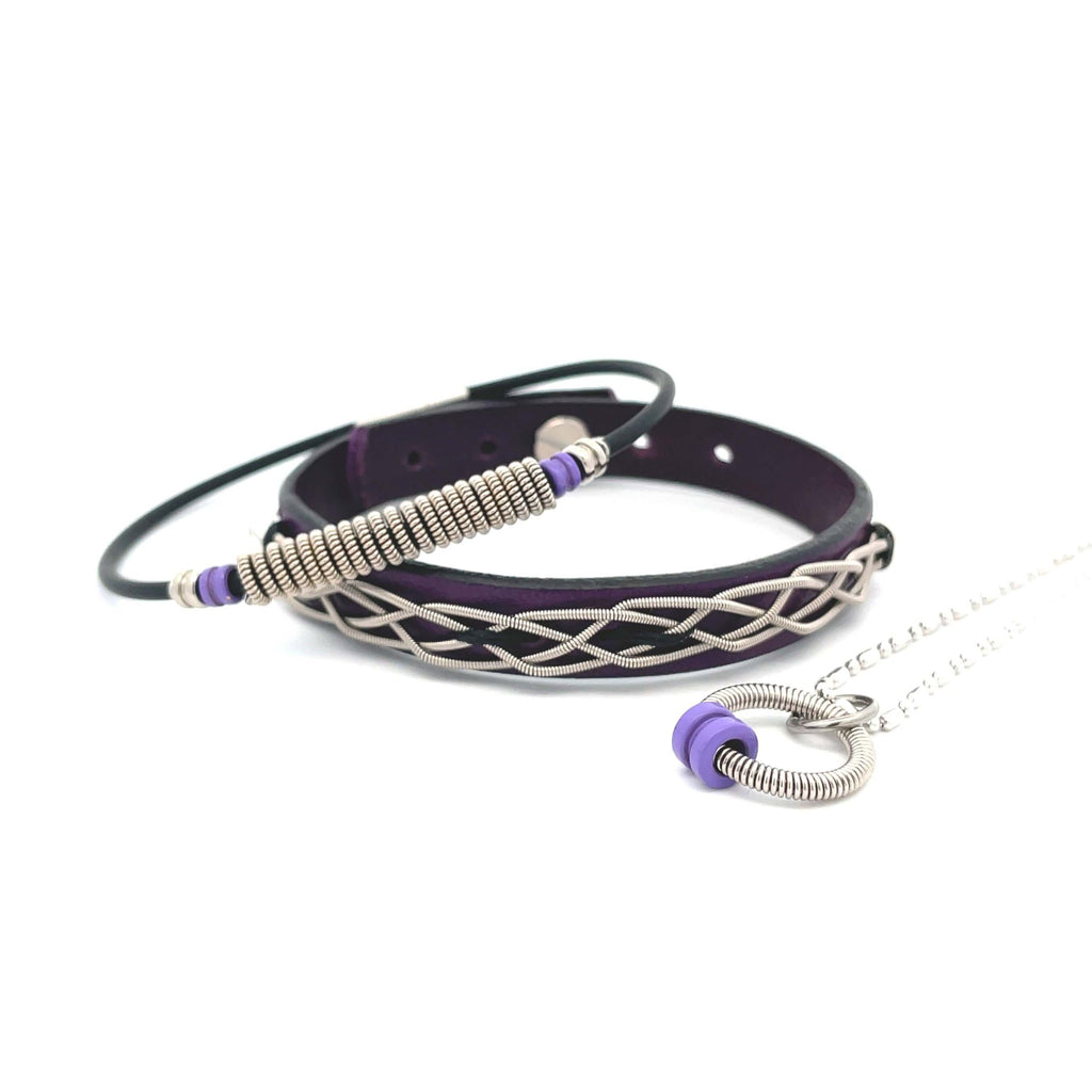 Purple leather electric guitar string bracelets and necklace on white background