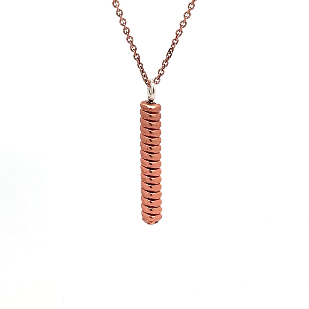 Piano string bar necklace with a rose gold chain hanging on a white background