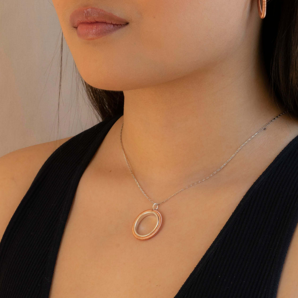 Piano string circle pendant on silver chain worn by model